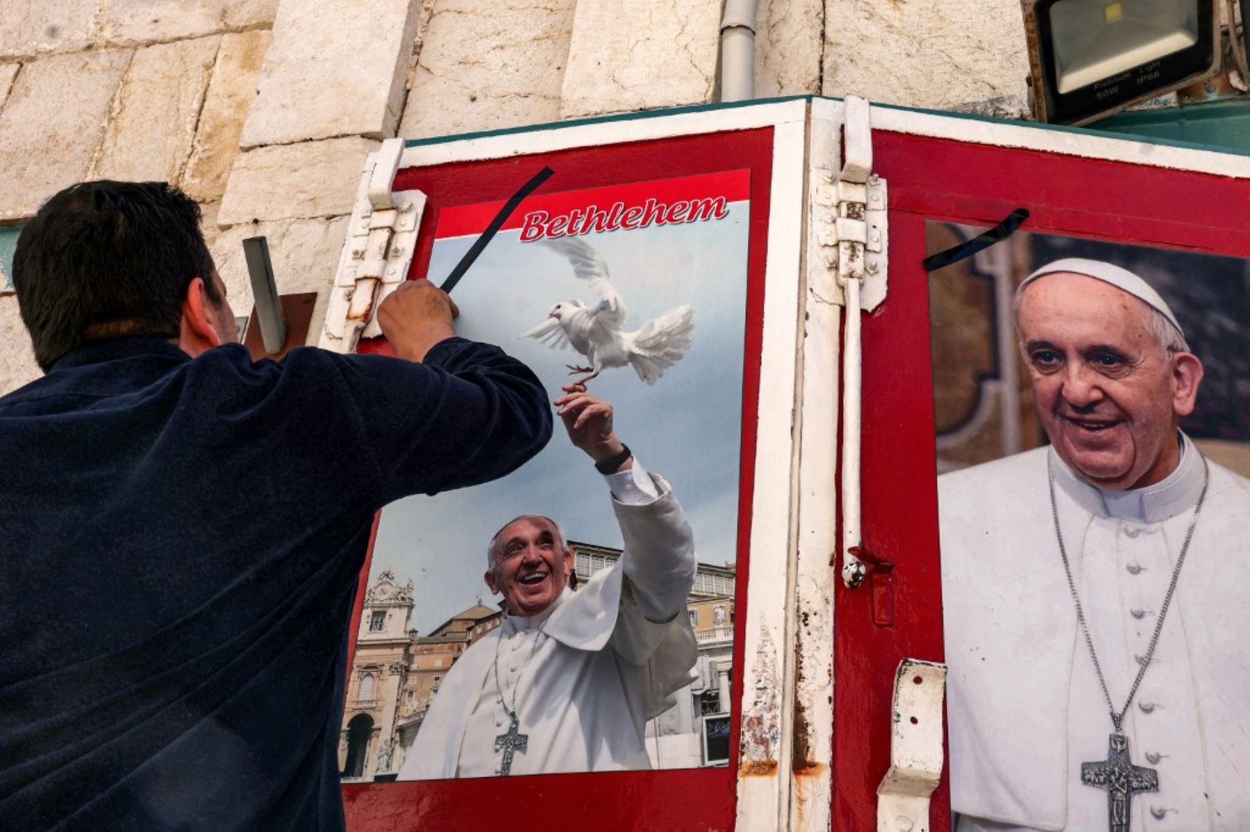 Un hombre toca una imagen del difunto Papa Francisco, expuesta en un cartel frente a una tienda en la ciudad bíblica de Belén, en la Cisjordania ocupada, el 21 de abril de 2025. Foto: AFP