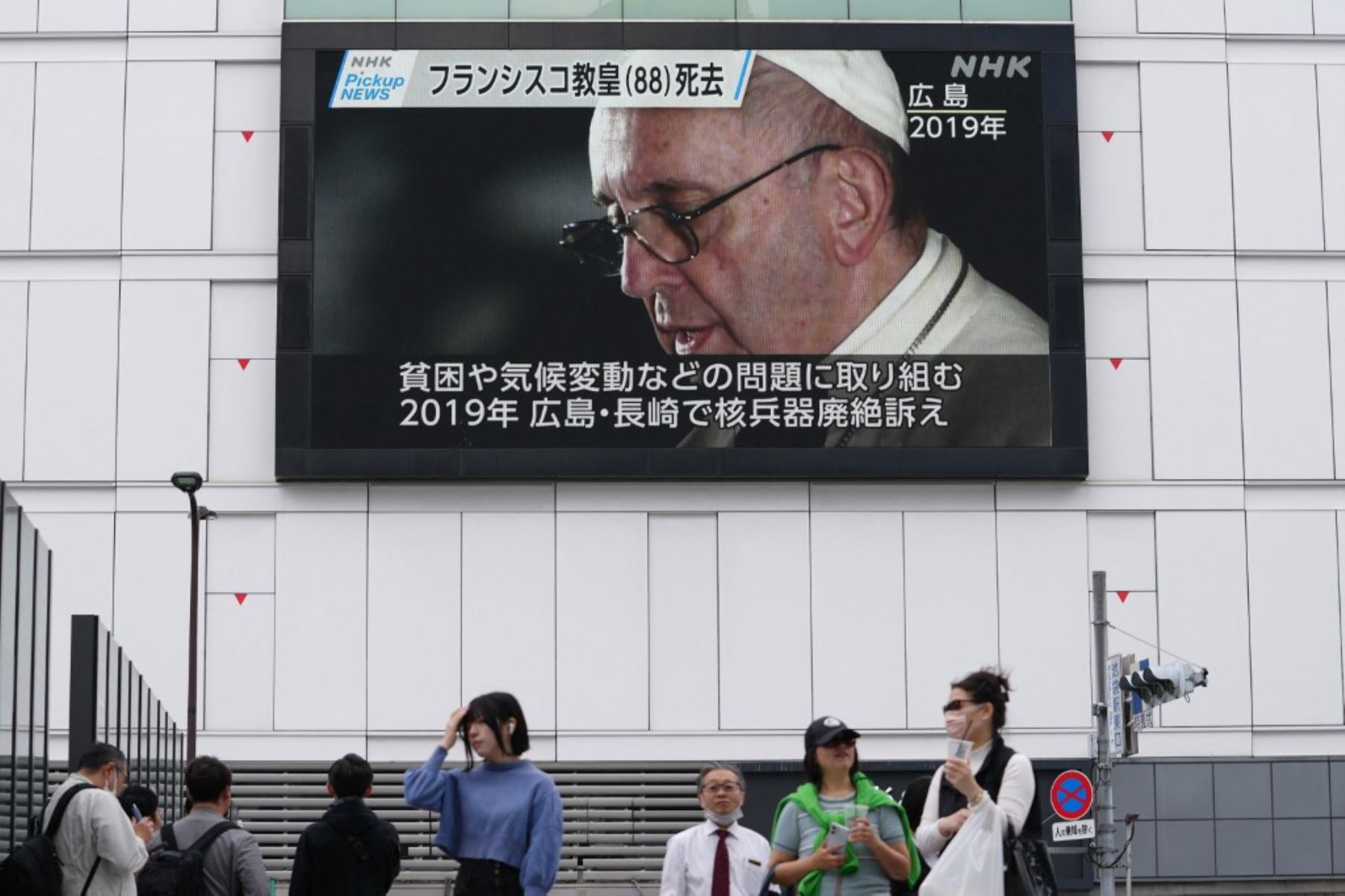 Peatones transitan por la calle durante una transmisión televisiva de noticias que muestra imágenes de archivo del Papa Francisco tras su fallecimiento en Tokio, Japón, el 22 de abril de 2025. Foto: AFP
