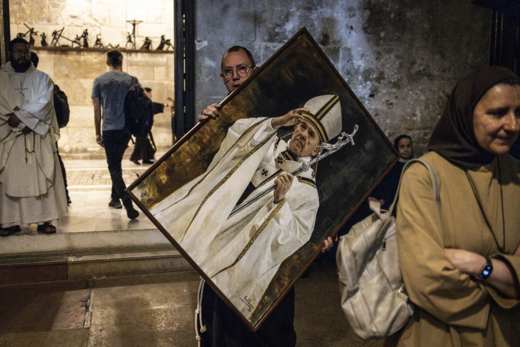 Un hombre porta un retrato del difunto Papa Francisco antes de una misa conmemorativa en la Iglesia del Santo Sepulcro en Jerusalén. Foto: AFP