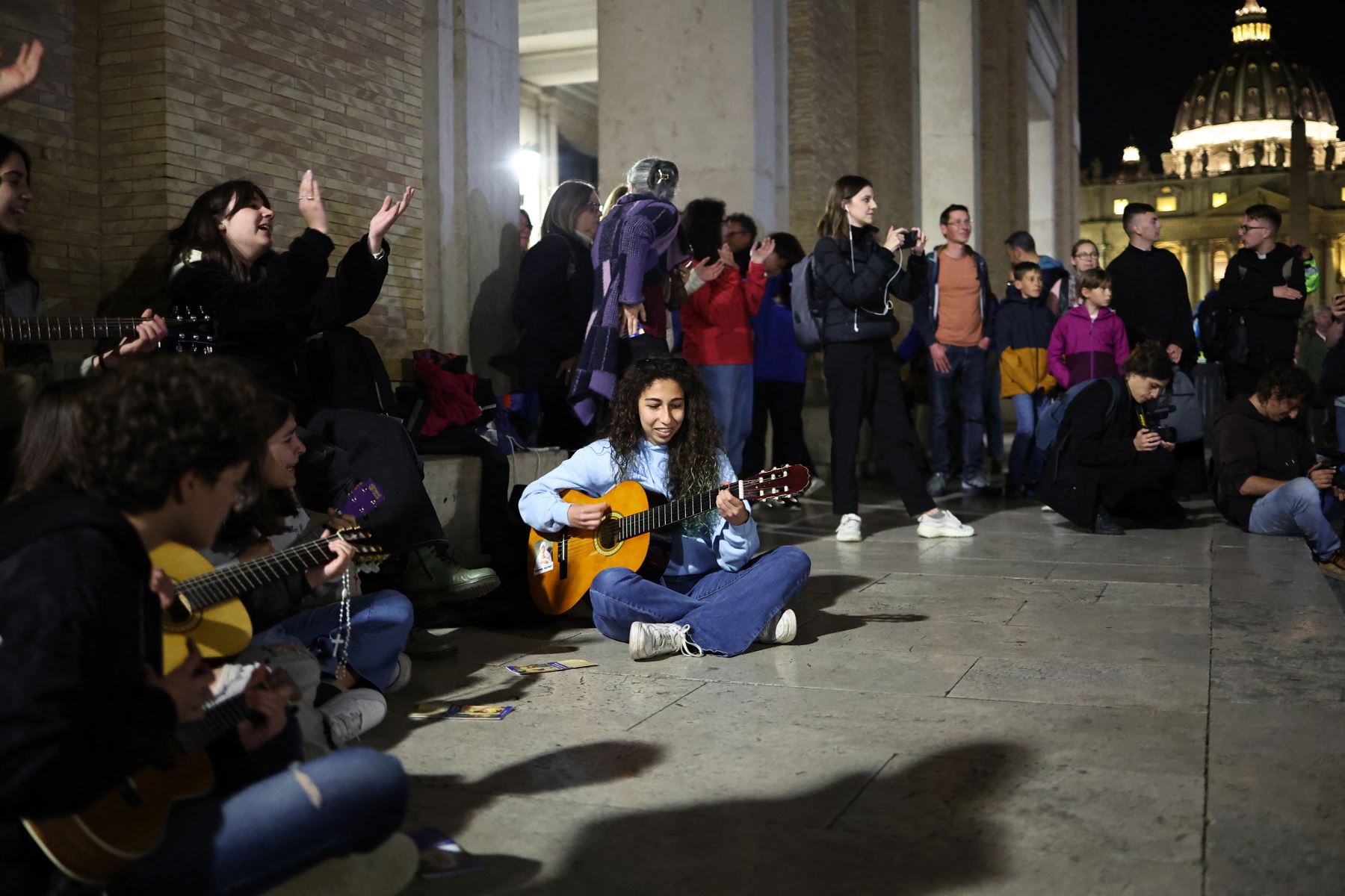 Jóvenes cristianos cantan canciones religiosas cerca de la Plaza de San Pedro, donde los visitantes y los dolientes hacen cola para acceder a la Basílica de San Pedro para presentar sus respetos al difunto Papa Francisco, en el Vaticano el 24 de abril de 2025. El Vaticano dijo el 24 de abril que unas 61.000 personas ya habían presentado sus respetos al Papa Francisco, cuyo cuerpo yace en estado en la Basílica de San Pedro antes de su funeral. AFP