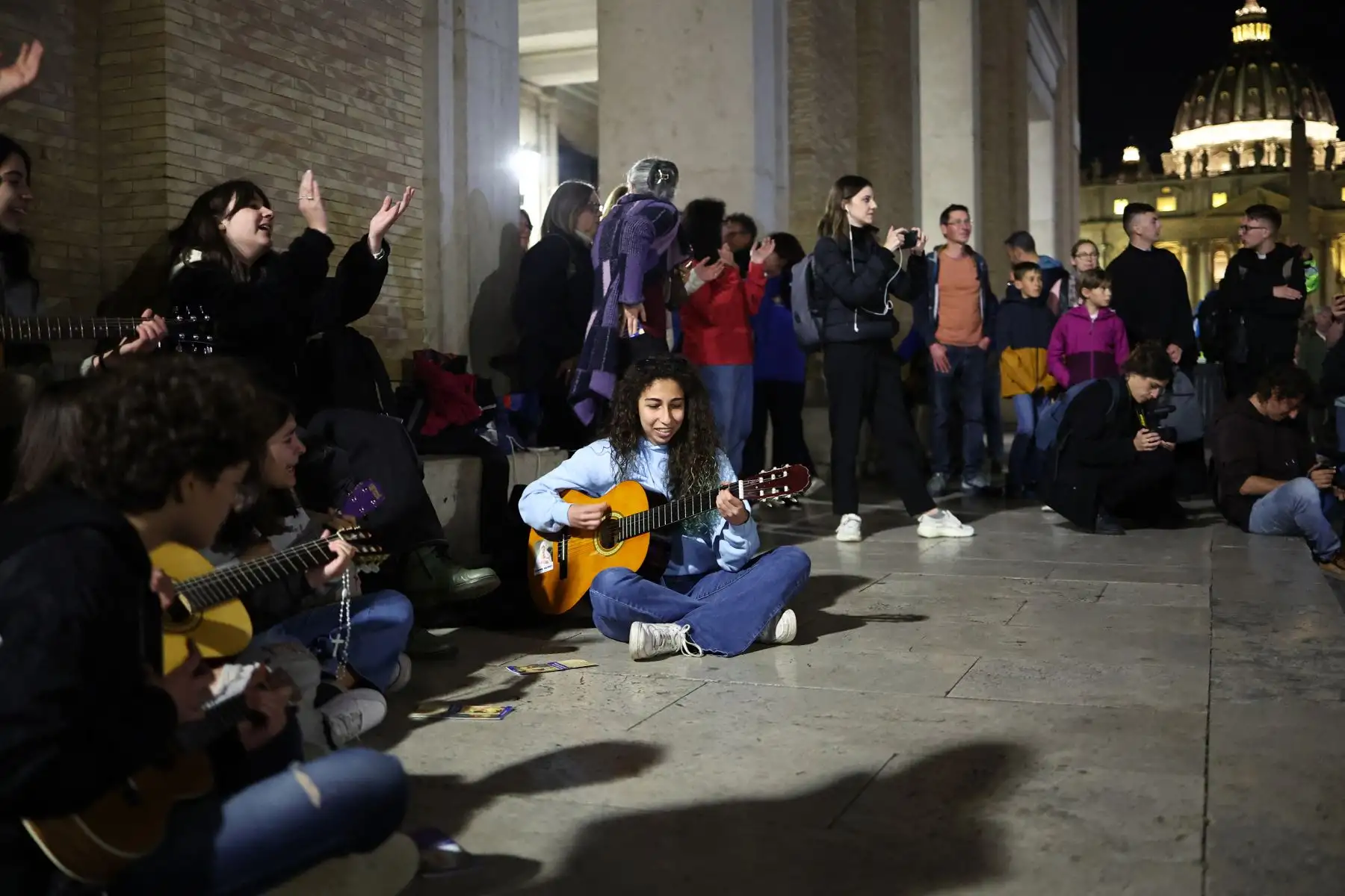 Jóvenes cristianos cantan canciones religiosas cerca de la Plaza de San Pedro, donde los visitantes y los dolientes hacen cola para acceder a la Basílica de San Pedro para presentar sus respetos al difunto Papa Francisco, en el Vaticano el 24 de abril de 2025. El Vaticano dijo el 24 de abril que unas 61.000 personas ya habían presentado sus respetos al Papa Francisco, cuyo cuerpo yace en estado en la Basílica de San Pedro antes de su funeral. AFP