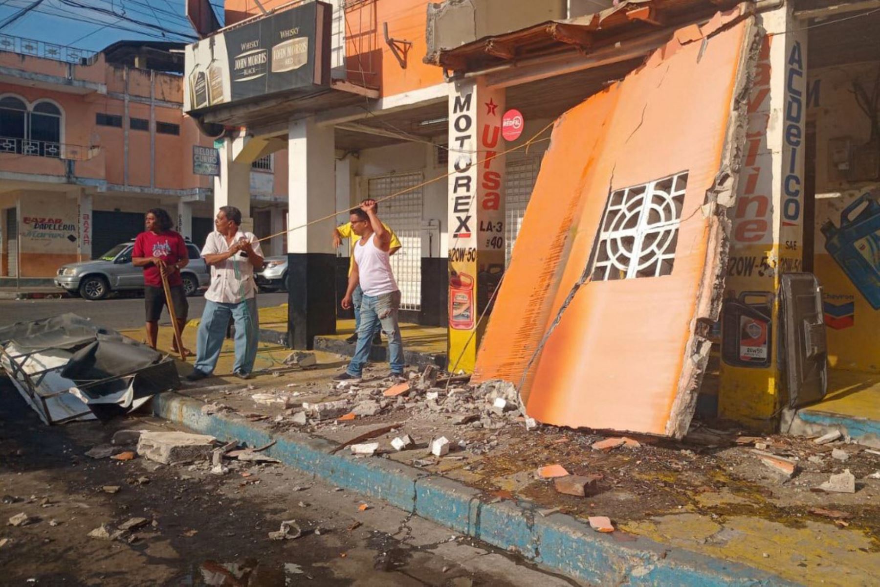 La gente permanece afuera de una tienda dañada después del terremoto que azotó la ciudad de Esmeraldas, Ecuador, el 25 de abril de 2025. Un sismo de magnitud 6,3 sacudió el viernes la provincia ecuatoriana de Esmeraldas, en el noroeste cerca de la frontera con Colombia. Foto: AFP