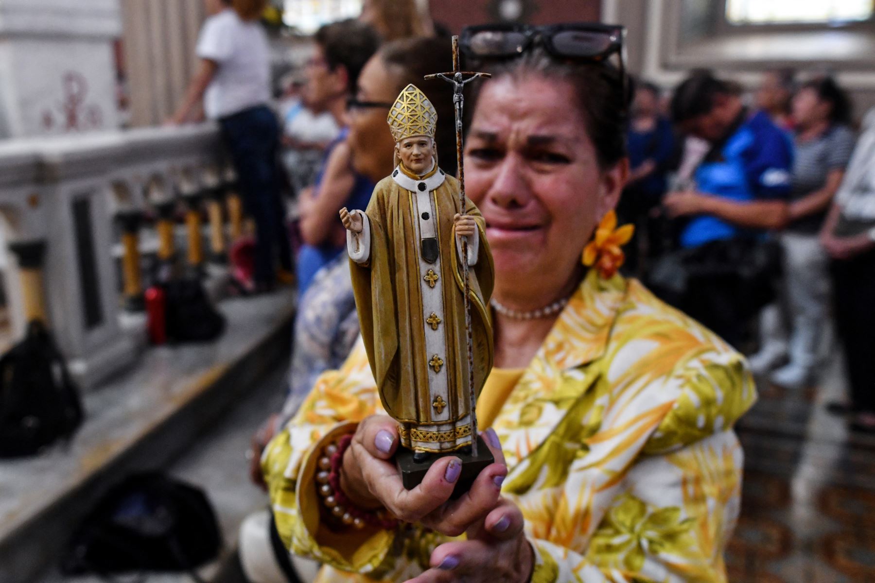 Una mujer reacciona mientras sostiene una figura que representa al Papa Juan Pablo II durante una misa en honor al fallecido Papa Francisco en la Catedral Metropolitana de San José. AFP