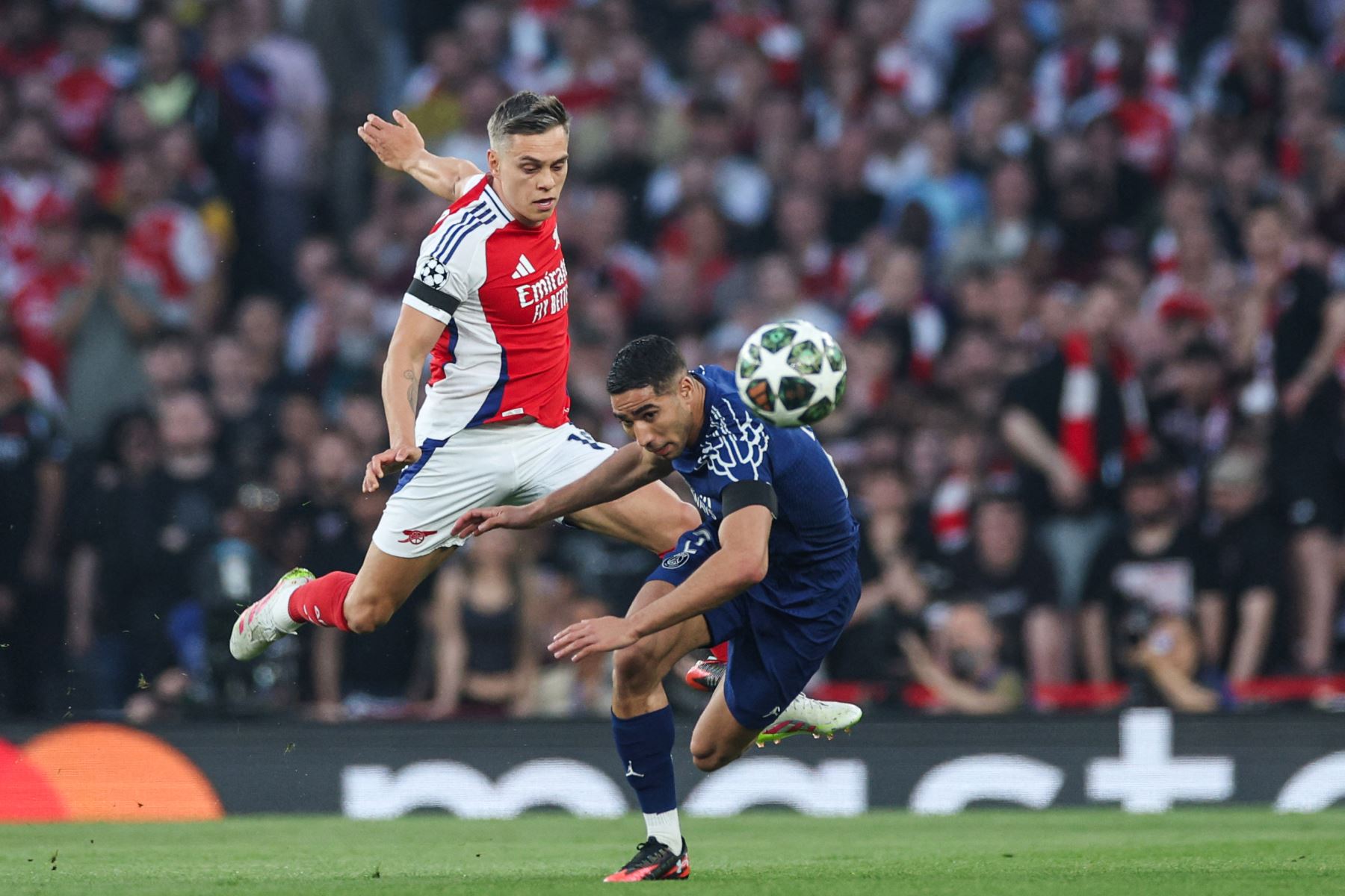 El centrocampista belga del Arsenal, Leandro Trossard, lucha por el balón con el defensor marroquí del Paris Saint-Germain, Achraf Hakimi, durante el partido de ida de la semifinal de la UEFA Champions League entre el Arsenal y el Paris Saint-Germain (PSG) en el Emirates Stadium en el norte de Londres, el 29 de abril de 2025. Foto: AFP