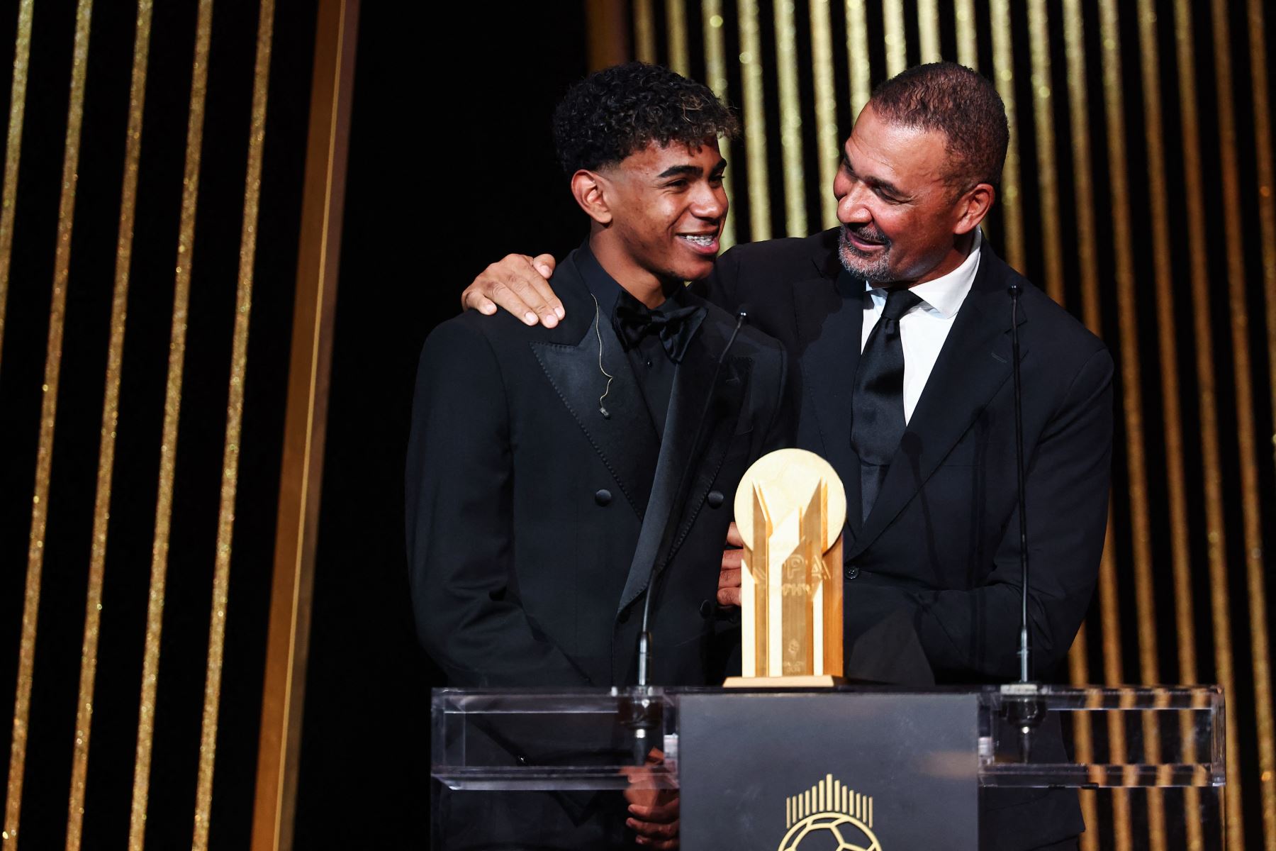El exfutbolista holandés Ruud Gullit (derecha) entrega el Trofeo Kopa al mejor jugador sub-21 al delantero español del Barcelona Lamine Yamal durante la ceremonia de entrega del Balón de Oro 2024 de France Football en el Théâtre du Châtelet de París. AFP