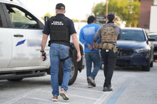 Agentes de la policía trasladan a un inmigrante detenido durante operativo. Foto: EFE/Archivo