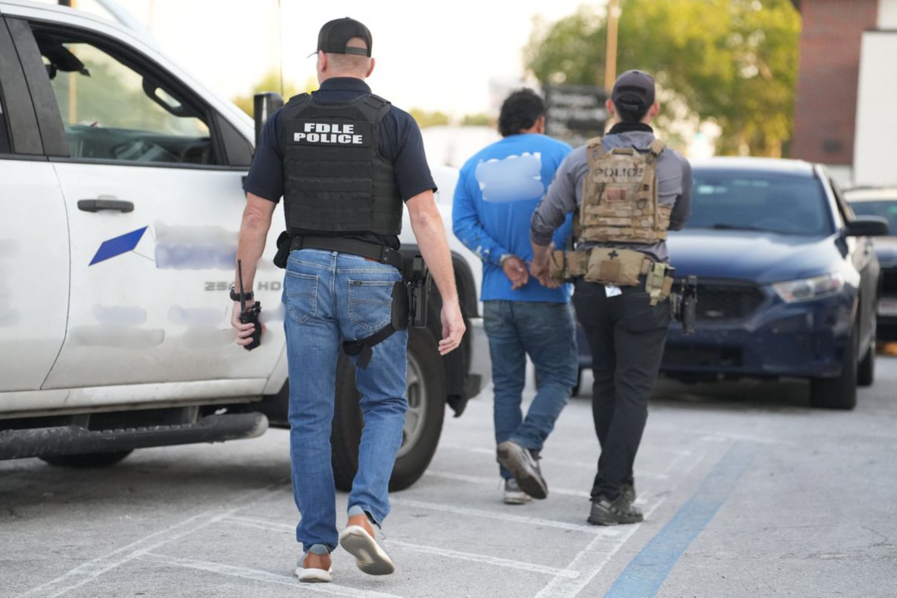 Agentes de la policía trasladan a un inmigrante detenido durante operativo. Foto: EFE/Archivo