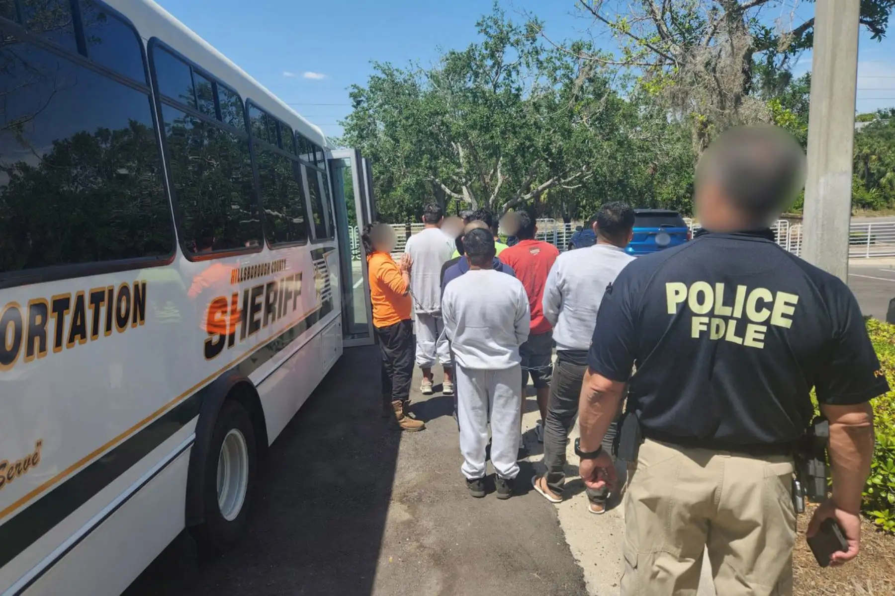 Agentes de la policía trasladan a inmigrantes detenidos durante la operación 