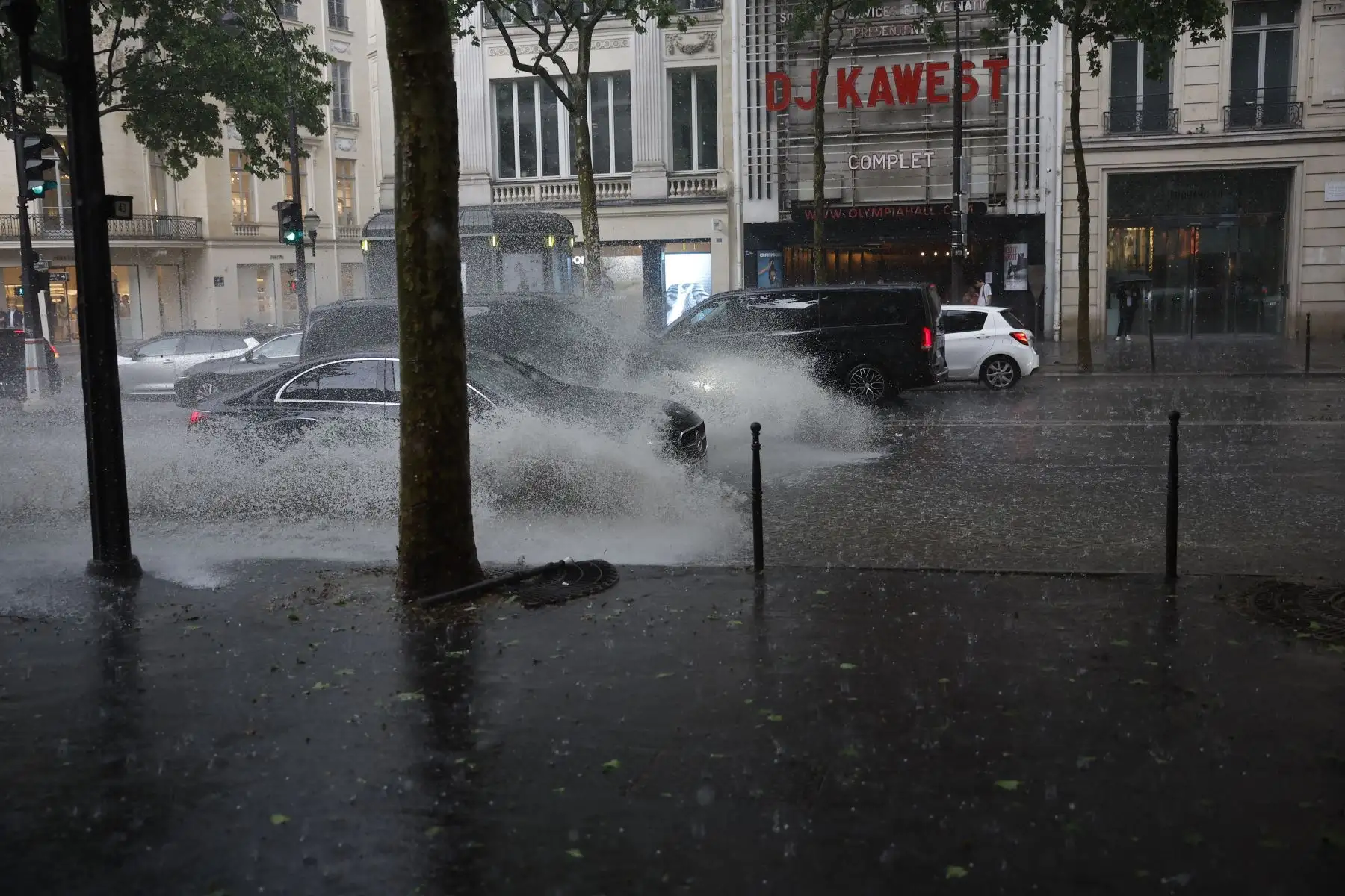 Los coches circulan por una calle inundada fuera del recinto de conciertos Olympia durante una tormenta de granizo en París. Foto: AFP