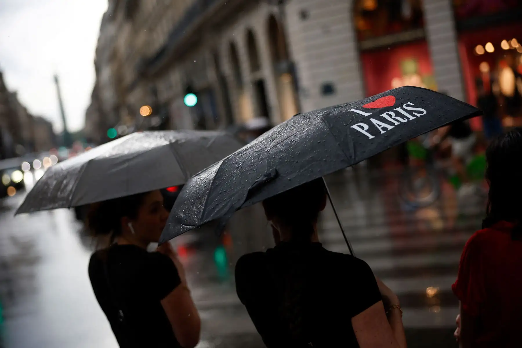 Las mujeres, una de ellas sosteniendo un paraguas con la leyenda "Amo París", están de pie en una calle después de una tormenta de granizo en París. AFP