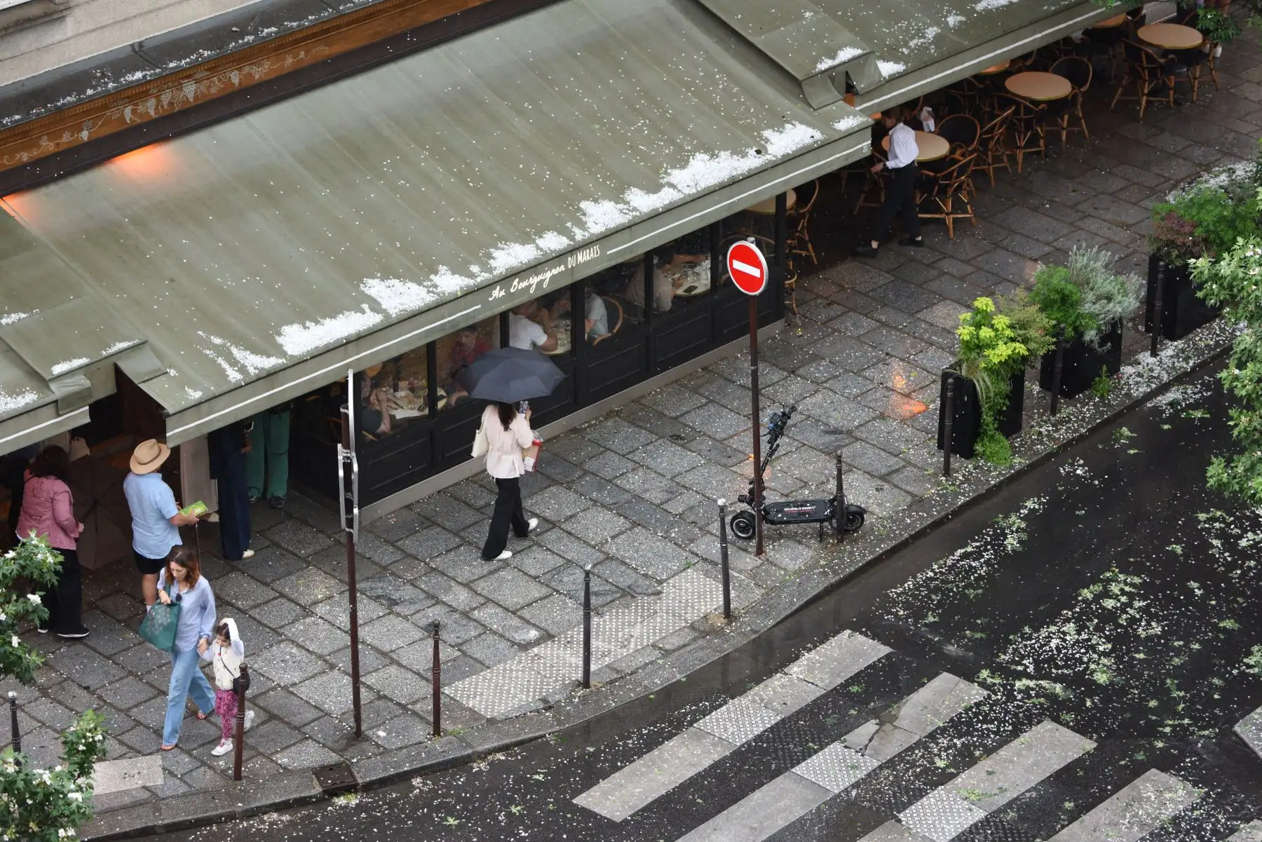 Mujeres, una de ellas con un paraguas, caminan por una calle después de una tormenta de granizo en París. AFP