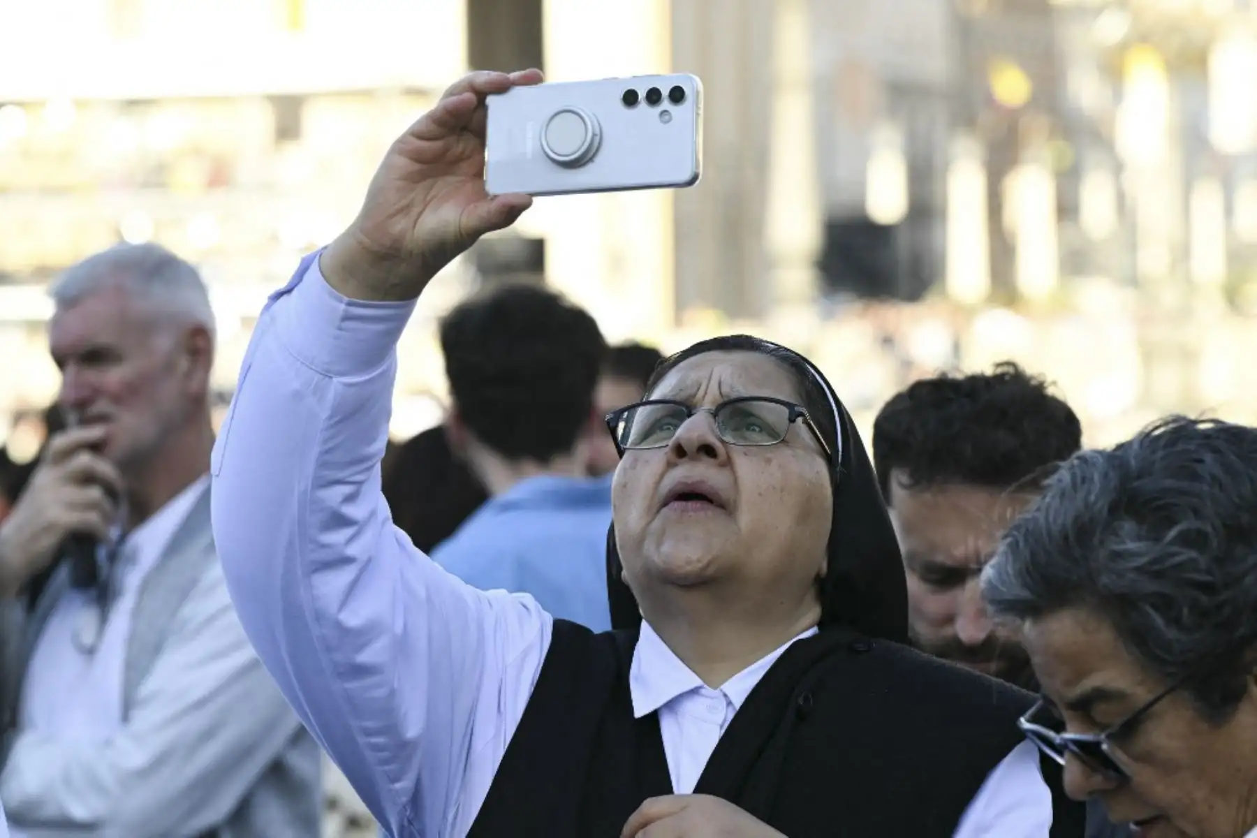 Una monja toma fotografías con su teléfono móvil mientras comienza el cónclave para elegir a un nuevo Papa, en la Plaza de San Pedro en el Vaticano

Foto: AFP