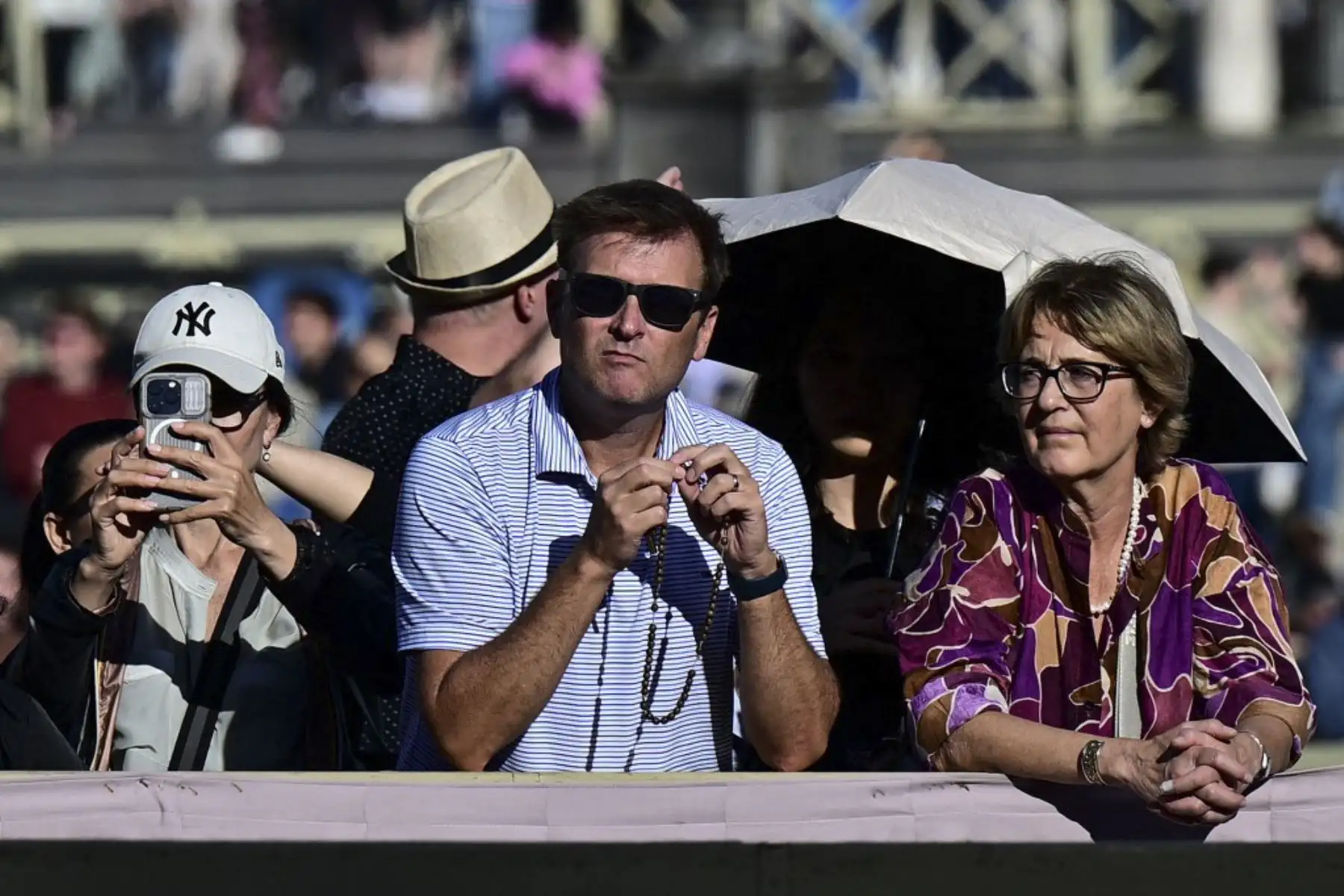 Una mujer se protege del sol mientras los fieles se reúnen en la Plaza de San Pedro antes del cónclave para elegir al próximo papa, en el Vaticano.

Foto: AFP