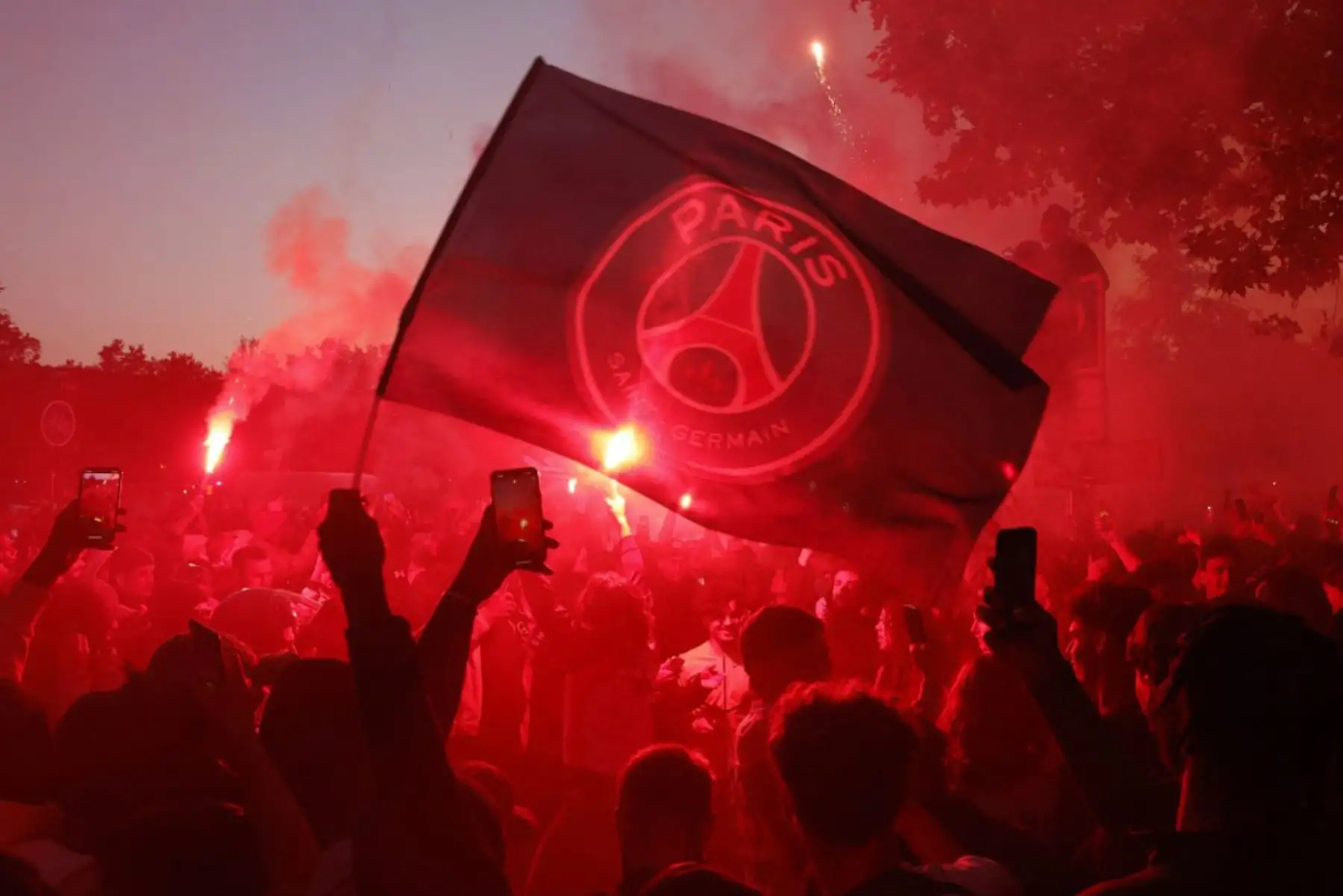Los hinchas del Paris Saint-Germain encienden bengalas y ondean una bandera con el logotipo del equipo mientras celebran el primer gol de su equipo durante el partido de vuelta de la semifinal de la UEFA Champions League entre el PSG y el Arsenal en la Place de Saint-Cloud, cerca del estadio Parc des Princes en París el 7 de mayo de 2025. Foto: AFP