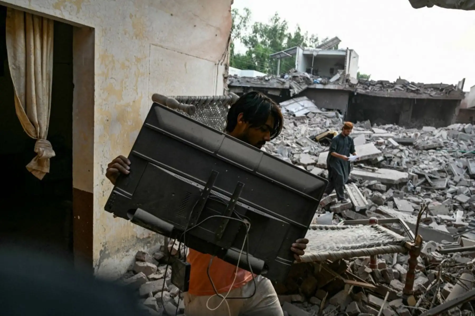 Un residente local recoge sus pertenencias entre los escombros de los edificios destruidos en el Complejo Gubernamental de Salud y Educación en Muridke, a unos 30 kilómetros de Lahore, Pakistán, el 7 de mayo de 2025, tras los ataques de La India. Foto: AFP