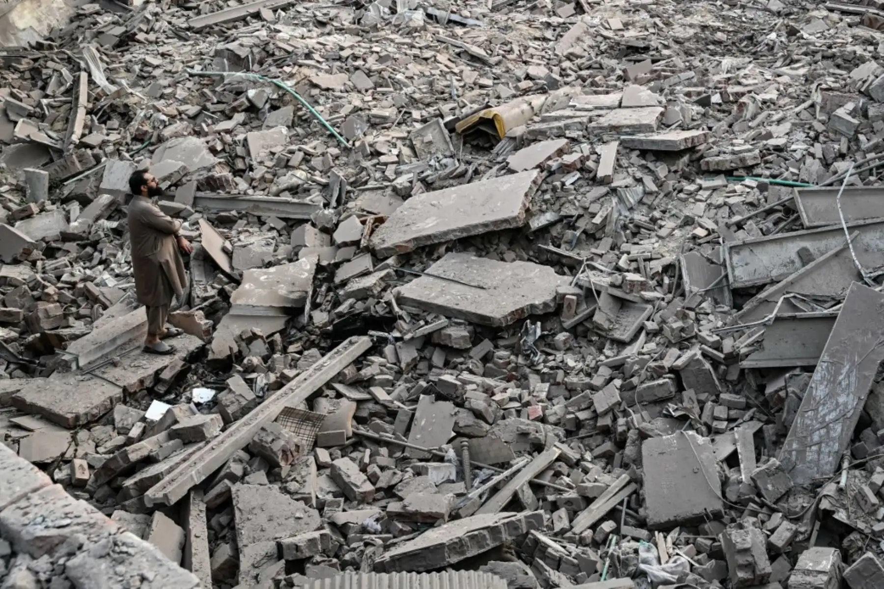 Residentes locales permanecen sobre los escombros de las estructuras destruidas en el complejo gubernamental de salud y educación en Muridke, a unos 30 kilómetros de Lahore, en Pakistán, el 7 de mayo de 2025, tras los ataques de La India. Foto: AFP