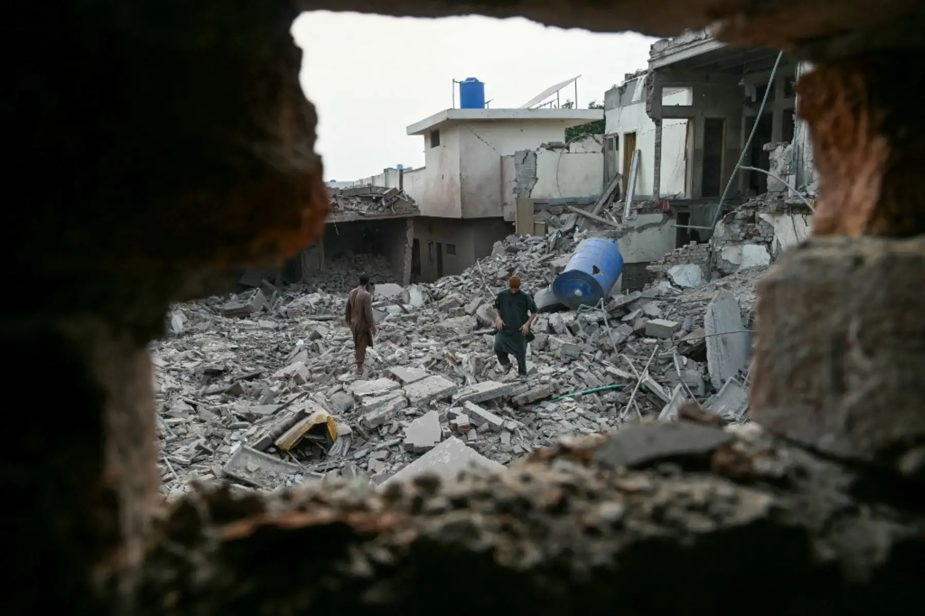 Residentes locales permanecen sobre los escombros de las estructuras destruidas en el complejo gubernamental de salud y educación en Muridke, a unos 30 kilómetros de Lahore, en Pakistán, el 7 de mayo de 2025, tras los ataques de La India. Foto: AFP