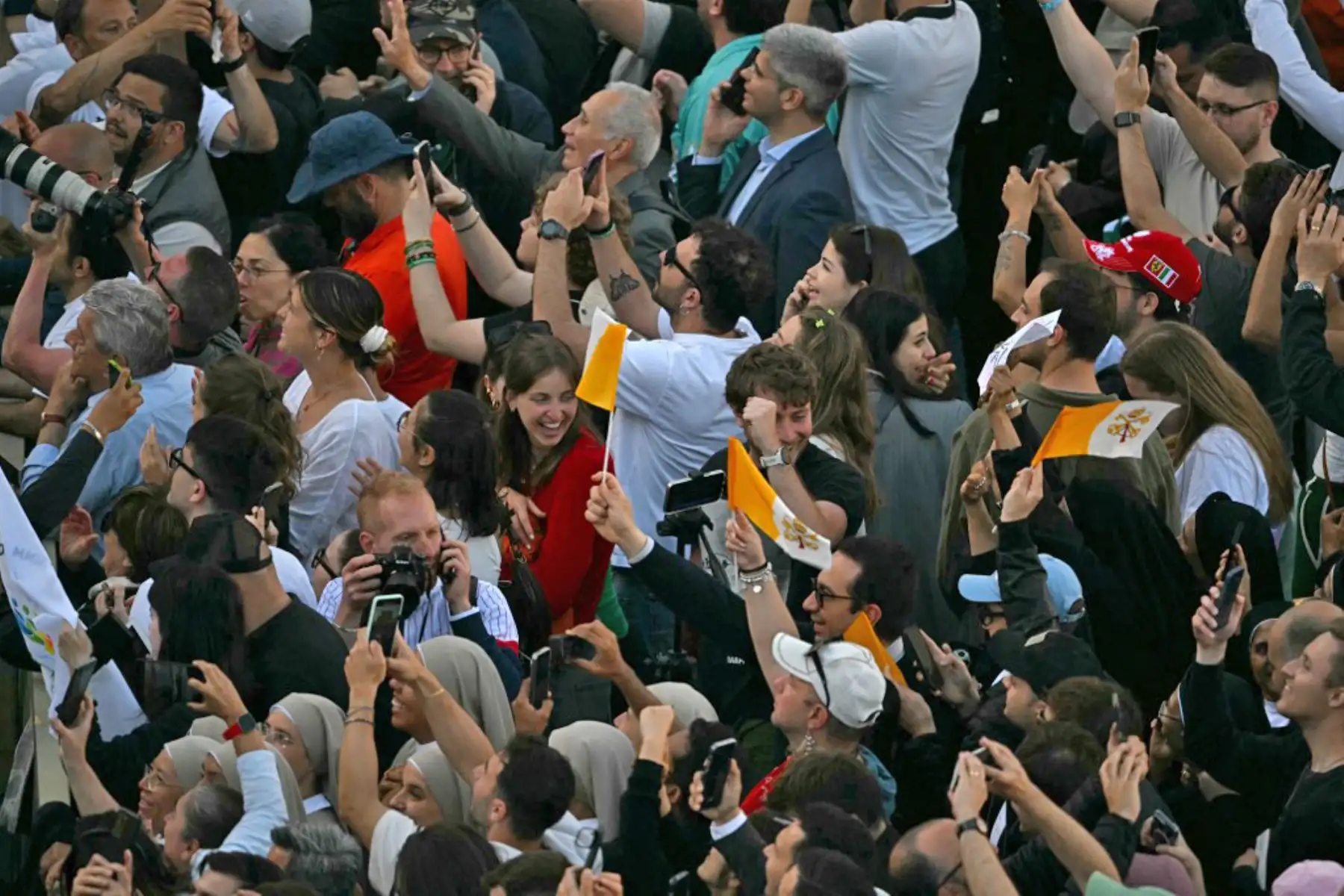 La gente reacciona y ondea banderas del Vaticano mientras una columna de humo blanco, anuncia que los cardenales eligieron un nuevo papa durante su cónclave en el Vaticano el 8 de mayo de 2025. Foto: AFP