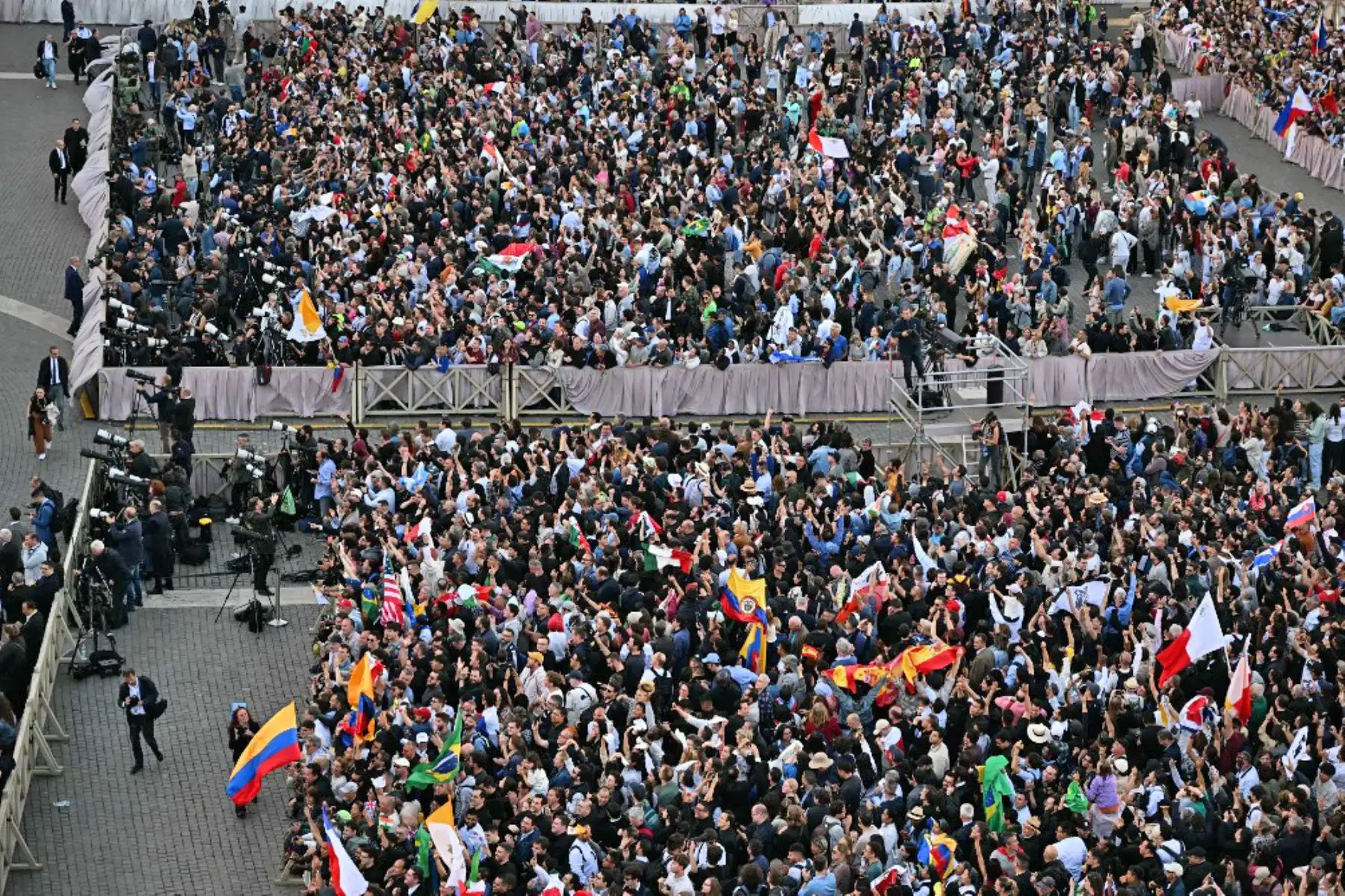 La gente reacciona y ondea banderas del Vaticano mientras una columna de humo blanco, anuncia que los cardenales eligieron un nuevo papa durante su cónclave en el Vaticano el 8 de mayo de 2025. Foto: AFP
