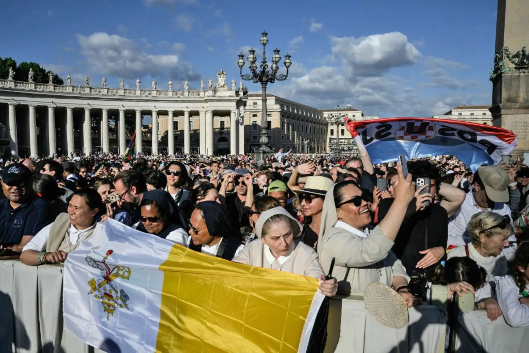 La gente reacciona y ondea banderas del Vaticano mientras una columna de humo blanco, anuncia que los cardenales eligieron un nuevo papa durante su cónclave en el Vaticano el 8 de mayo de 2025. Foto: AFP