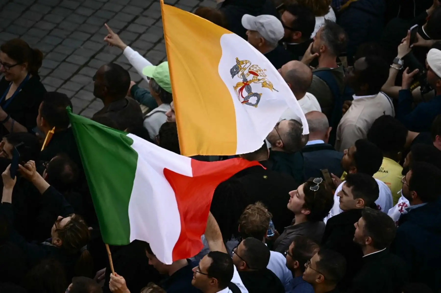 La gente reacciona y ondea banderas del Vaticano mientras una columna de humo blanco, anuncia que los cardenales eligieron un nuevo papa durante su cónclave en el Vaticano el 8 de mayo de 2025. Foto: AFP