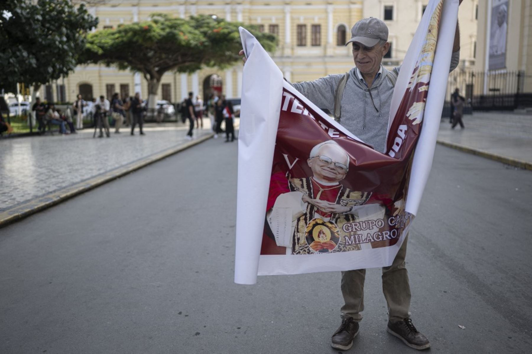 Un hombre abre una pancarta con la imagen del Papa León XIV frente a la catedral de Chiclayo, Perú. Foto: AFP