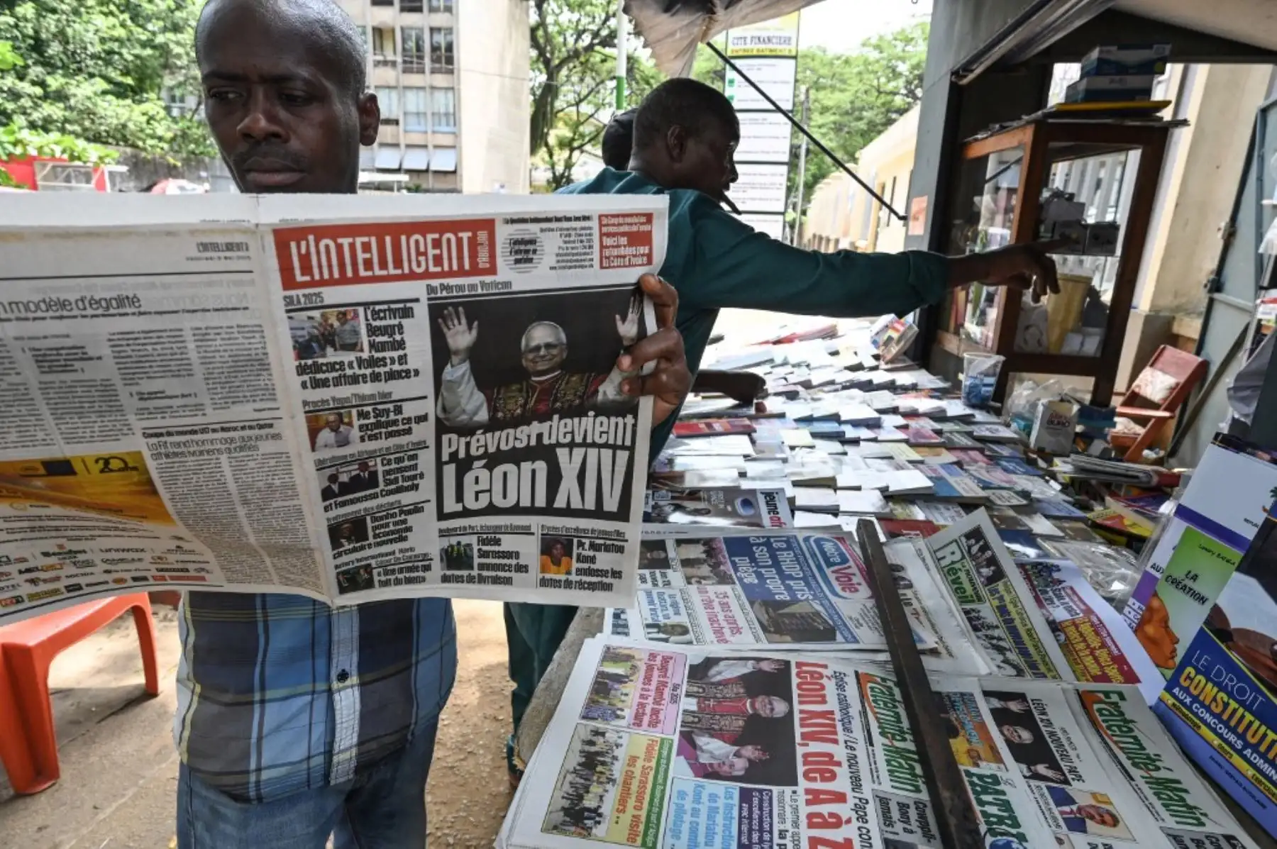 Un hombre lee un diario, cuya portada presenta titulares e imágenes que anuncian al recién elegido papa León XIV, Robert Prevost, en Abiyán, Costa de Marfil, el 9 de mayo de 2025. Foto: AFP