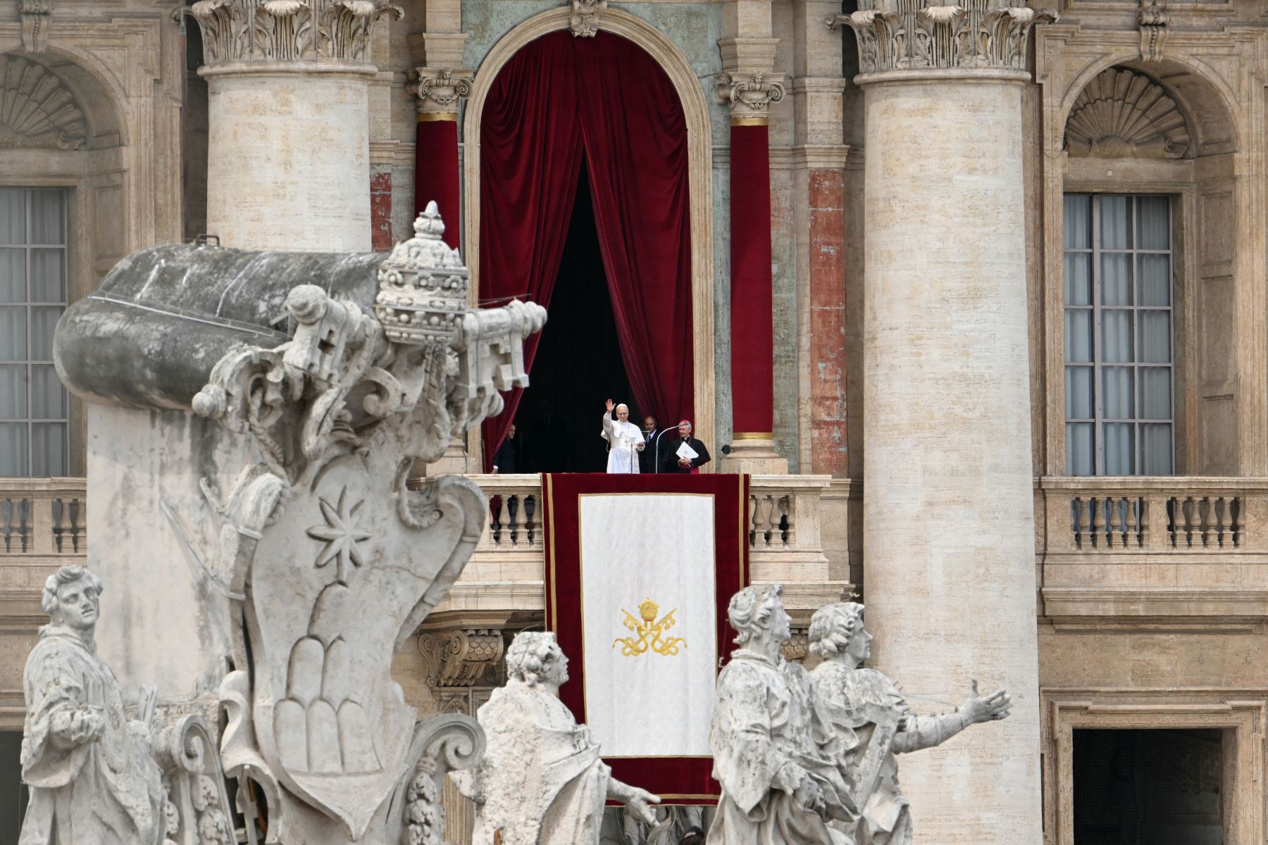 El Papa León XIV (izq.) reza el Regina Caeli desde la logia central de la basílica de San Pedro en el Vaticano. AFP
