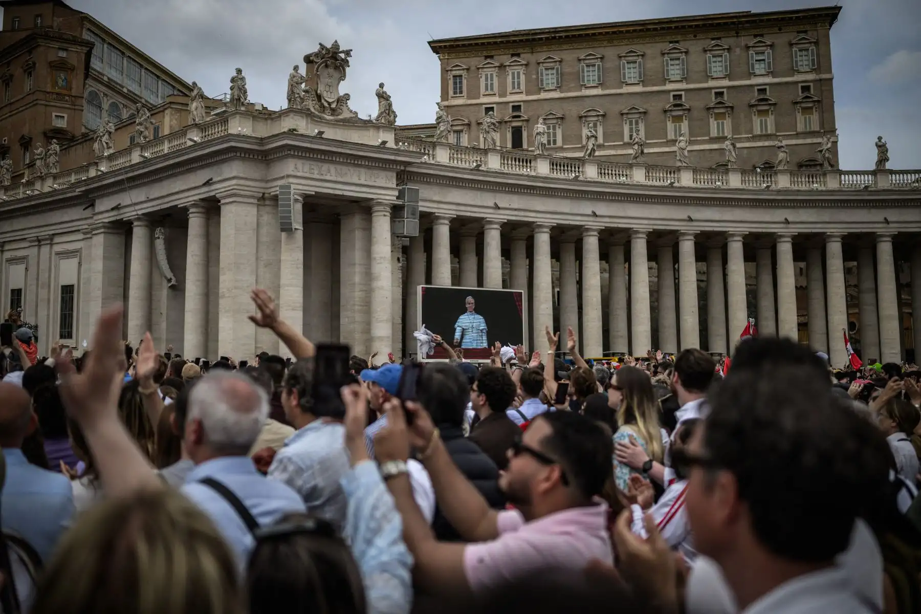 Los fieles saludan mientras se ve al Papa León XIV en una pantalla gigante mientras pronuncia su primera oración del Regina Caeli, en la plaza de San Pedro en el Vaticano. AFP