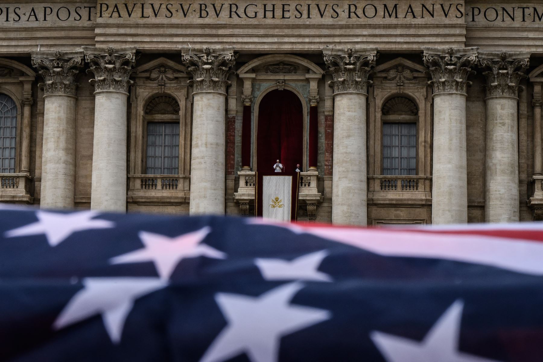 Una bandera estadounidense ondea mientras el Papa León XIV pronuncia la oración del Regina Caeli desde la logia central de la basílica de San Pedro en el Vaticano. AFP