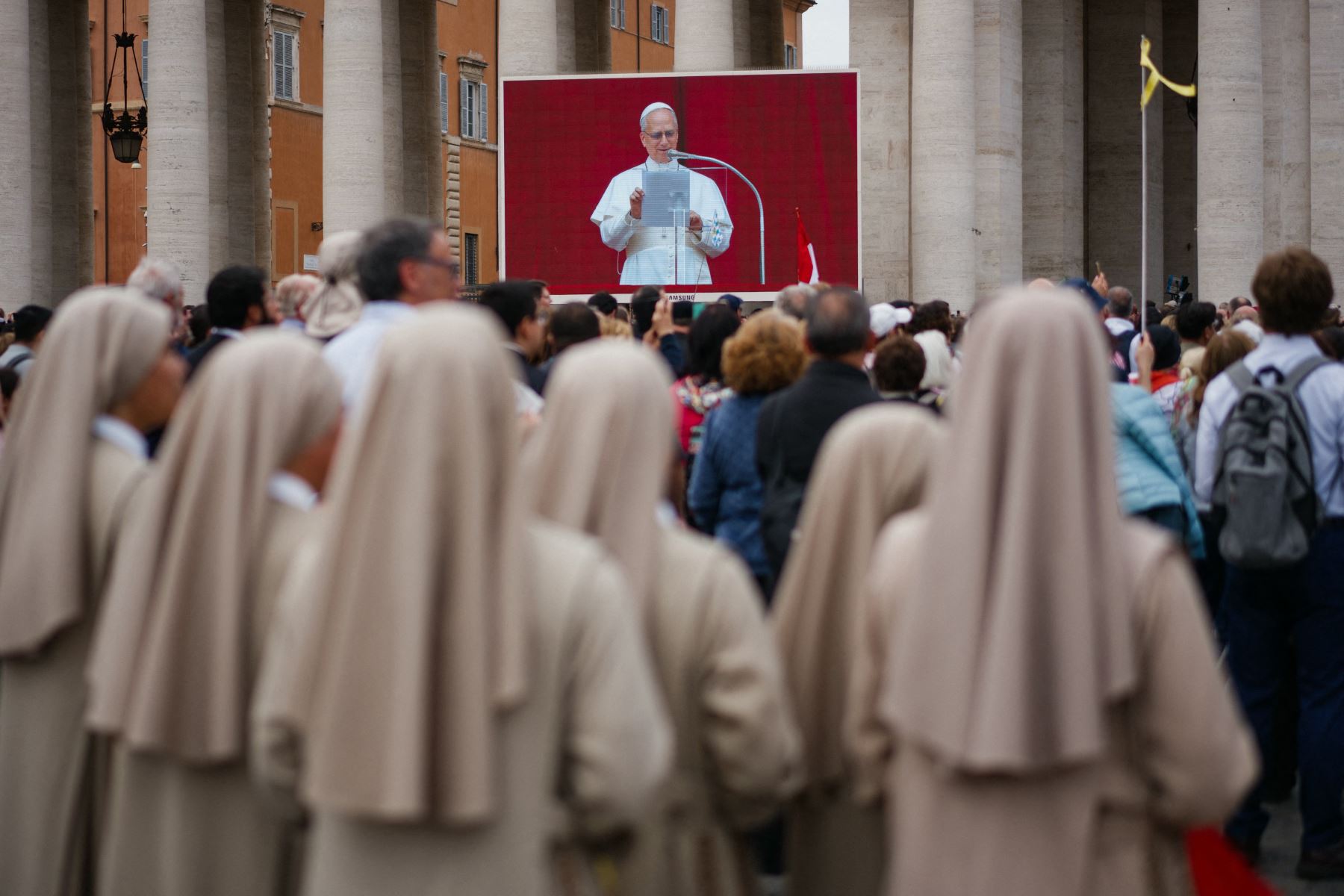 Los fieles observan una pantalla en la plaza de San Pedro que muestra al Papa León XIV dirigiendo la oración del Regina Caeli, en el Vaticano. AFP