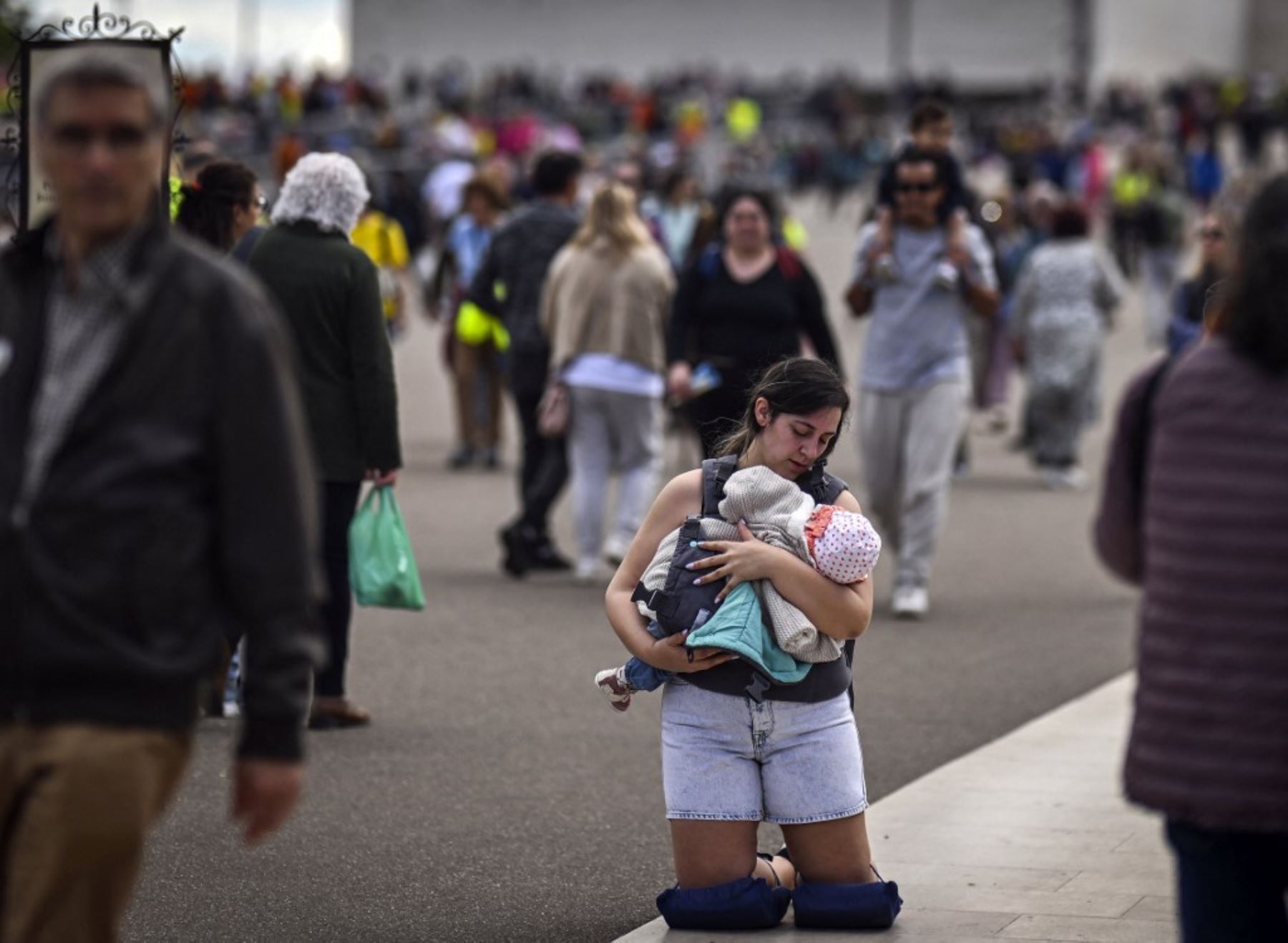 Una peregrina camina de rodillas con su hijo en brazos en el Santuario de Fátima, en Fátima, centro de Portugal. Foto: AFP