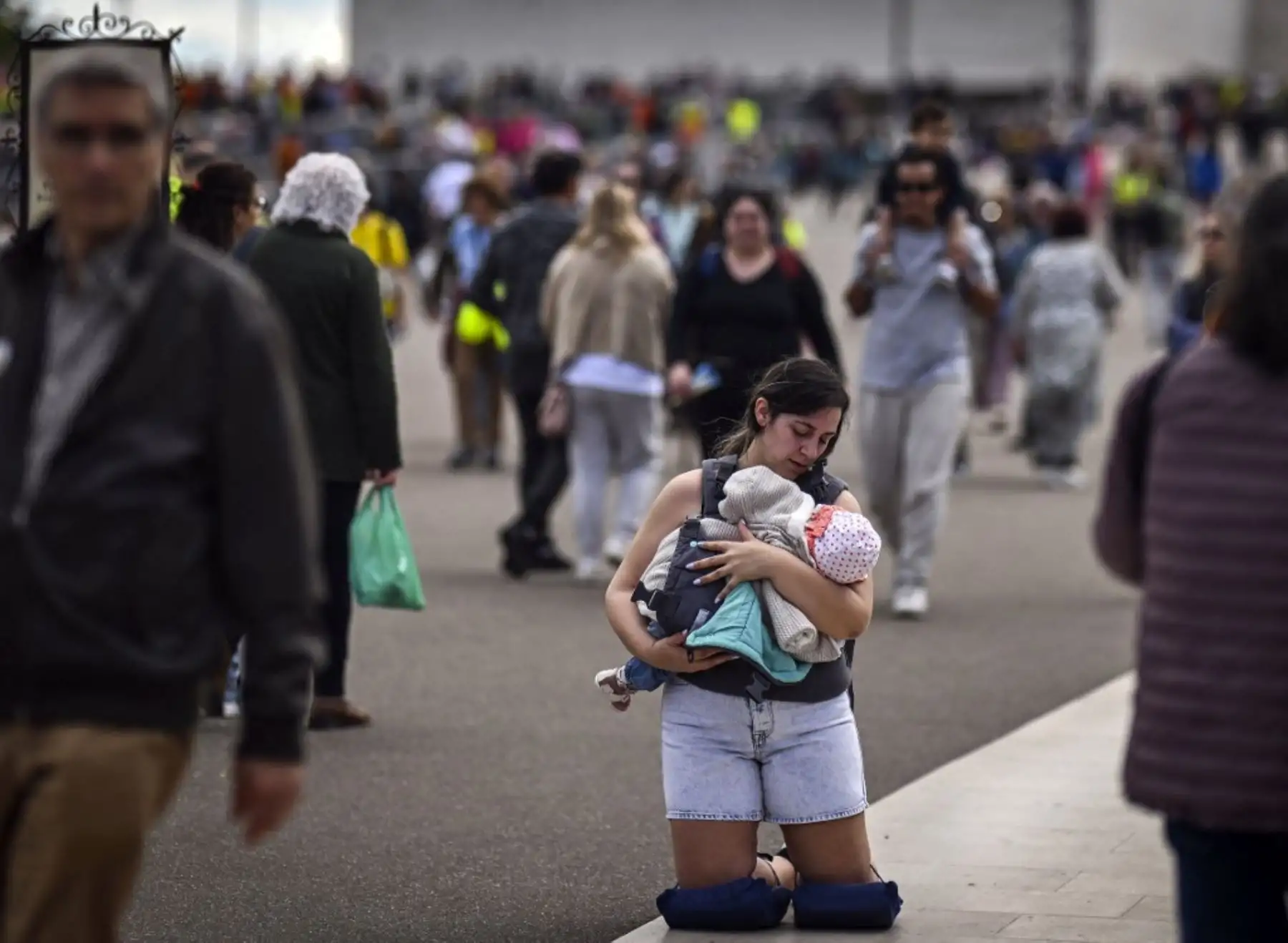 Una peregrina camina de rodillas con su hijo en brazos en el Santuario de Fátima, en Fátima, centro de Portugal. Foto: AFP