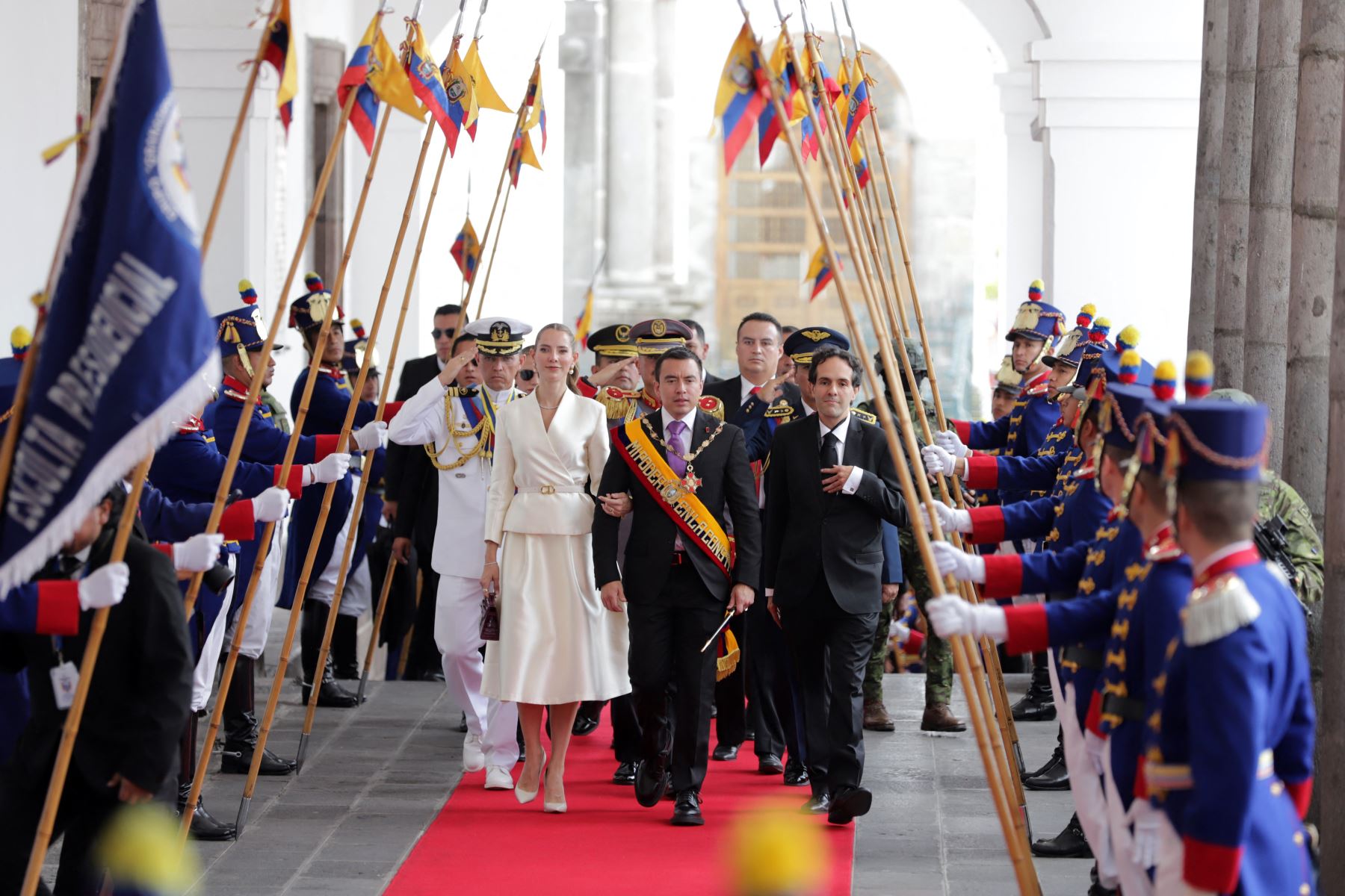 El presidente reelecto de Ecuador, Daniel Noboa, y su esposa, la primera dama Lavinia Valbonesi (I), acompañados por el jefe de protocolo del presidente, Mario Gallegos (D), reciben honores a su ingreso al Palacio de Carondelet luego de su investidura en la Asamblea Nacional en Quito. AFP