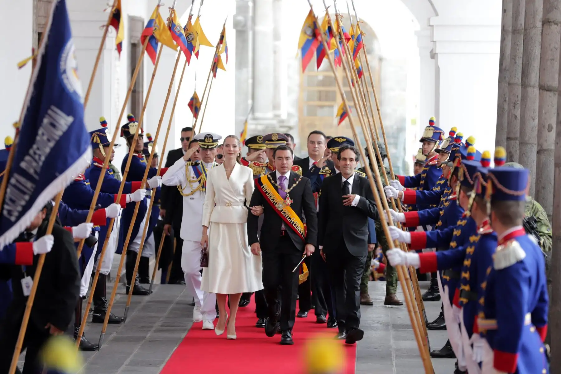 El presidente reelecto de Ecuador, Daniel Noboa, y su esposa, la primera dama Lavinia Valbonesi (I), acompañados por el jefe de protocolo del presidente, Mario Gallegos (D), reciben honores a su ingreso al Palacio de Carondelet luego de su investidura en la Asamblea Nacional en Quito. AFP