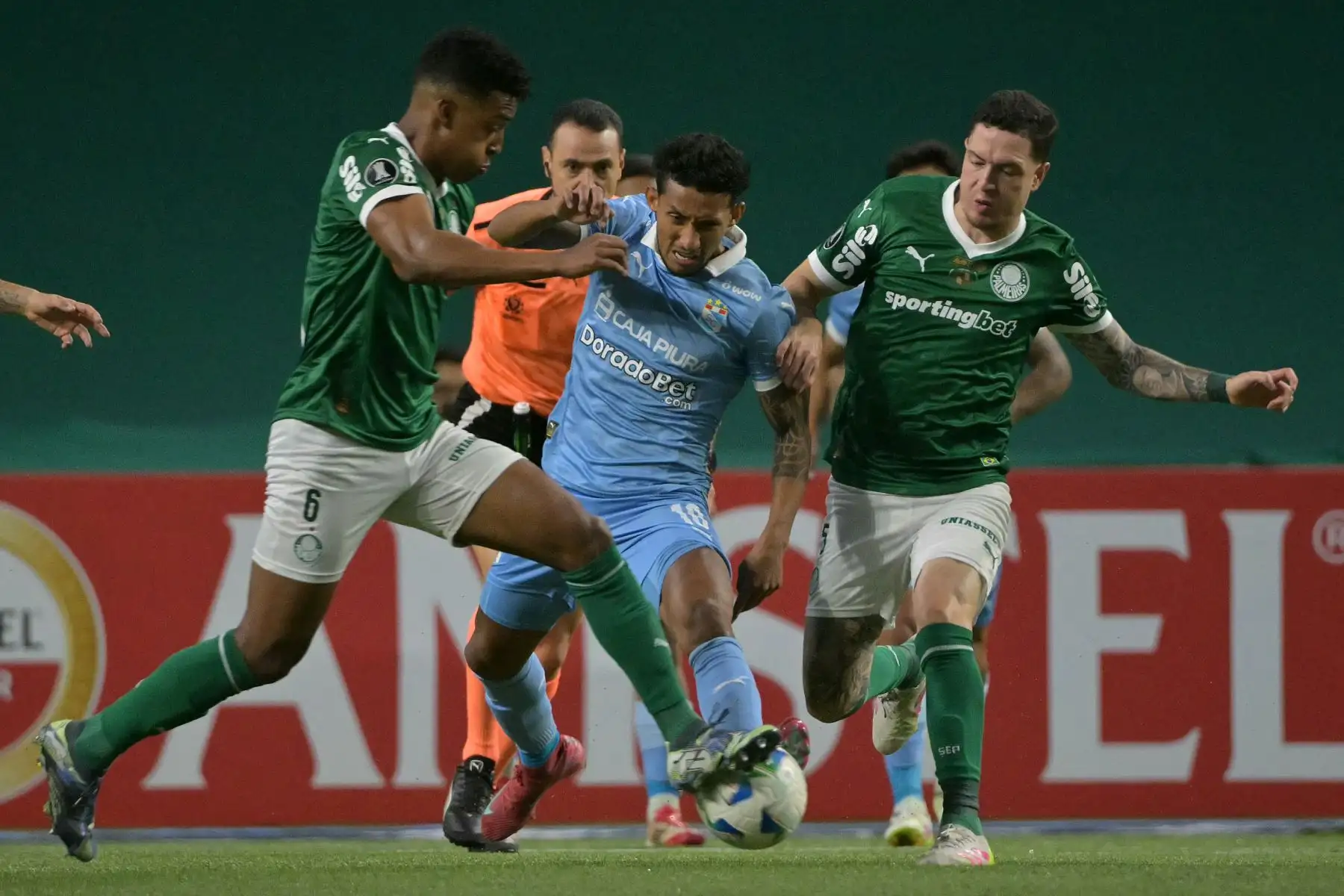 El mediocampista de Sporting Cristal, Christofer Gonzales, lucha por el balón con los jugadores de Palmeiras, Vanderlan y Anibal Moreno, durante el partido de fútbol de la fase de grupos de la Copa Libertadores entre Palmeiras de Brasil y Sporting Cristal de Perú en el estadio Allianz Parque en Sao Paulo. Foto: AFP