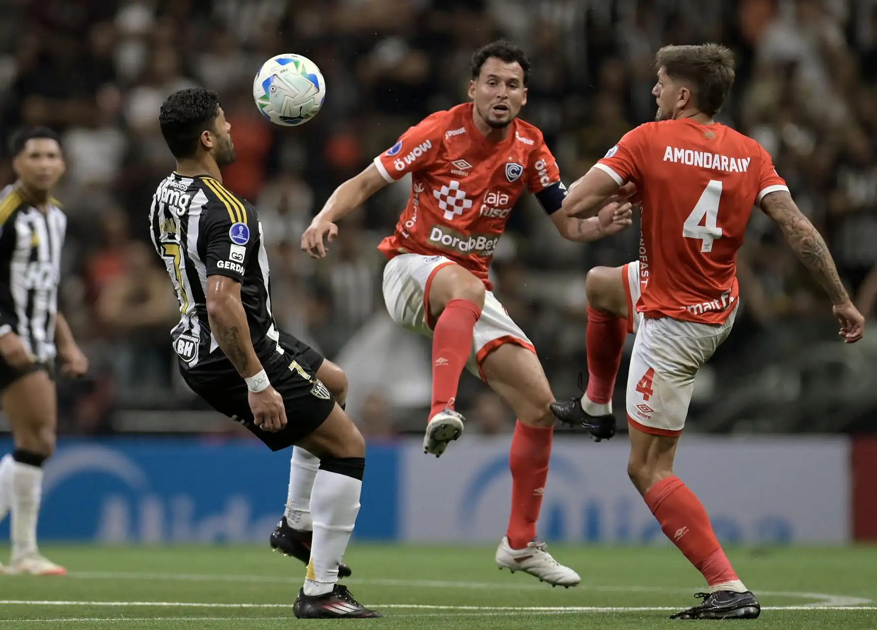 El delantero  Hulk del Atlético Mineiro pasa el balón por encima del mediocampista  Claudio Torrejón del Cienciano y del defensor uruguayo Maximiliano Amondarain durante el partido de la fase de grupos de la Copa Sudamericana entre el Atlético Mineiro de Brasil y el Cienciano de Perú. AFP