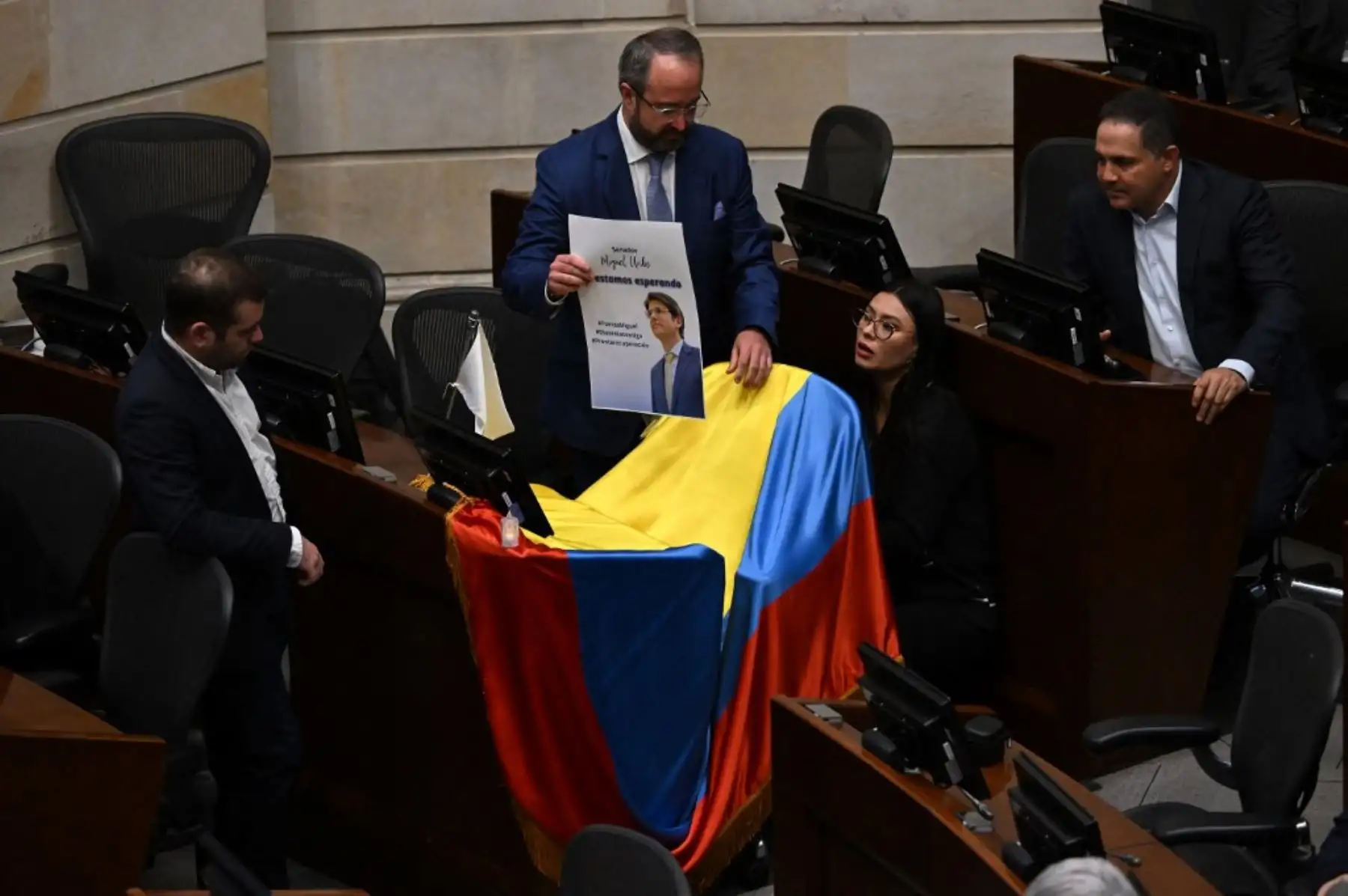 Legisladores colocan una foto del senador y candidato presidencial colombiano Miguel Uribe con la frase "Te esperamos" en una bandera colombiana sobre su escaño en el Congreso en Bogotá el 9 de junio de 2025. Foto: AFP