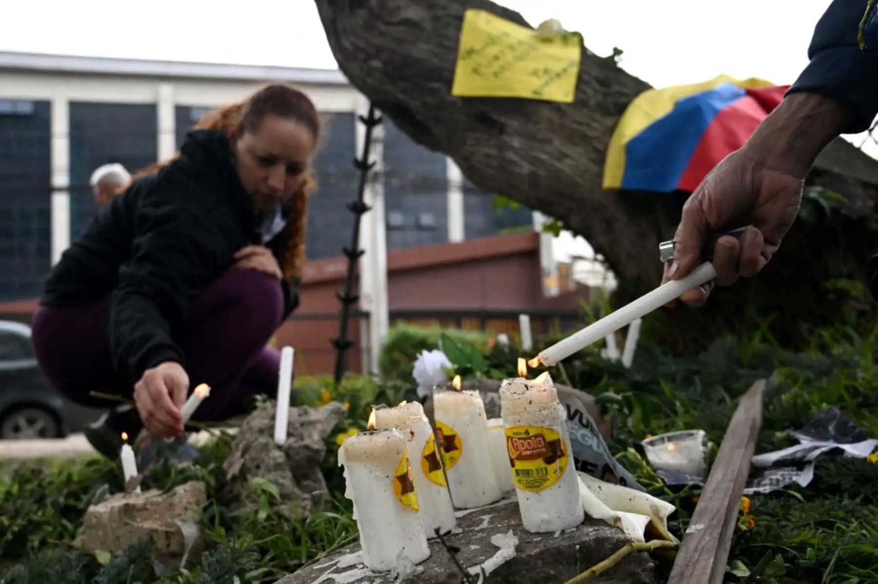 Una mujer enciende una vela en el lugar donde el senador Miguel Uribe Turbay fuera baleado y herido en un acto político el pasado sábado en Bogotá el 9 de junio de 2025. Foto: AFP