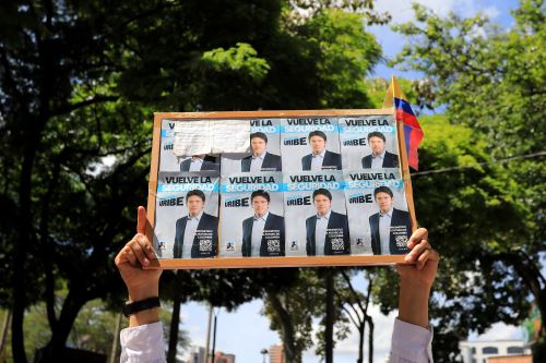 Un manifestante sostiene afiches con la fotografía de Miguel Uribe Turbay, durante una manifestación a favor de la paz en Medellín. Foto: AFP