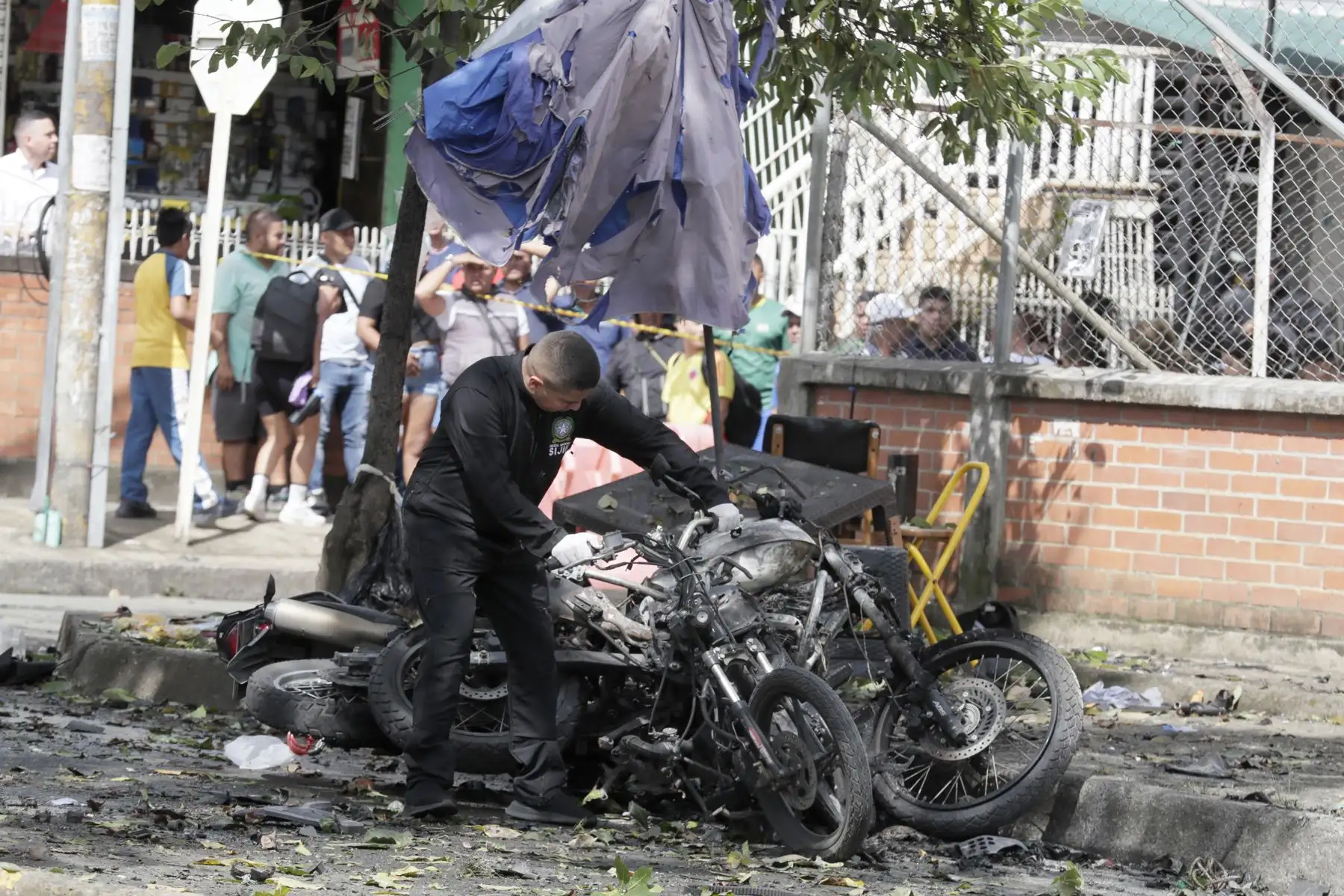 Un integrante de la policía levanta los escombros de una motocicleta en los alrededores de la estación de policía del barrio Meléndez donde ocurrió un atentado este martes, al sur de Cali (Colombia). Foto: EFE