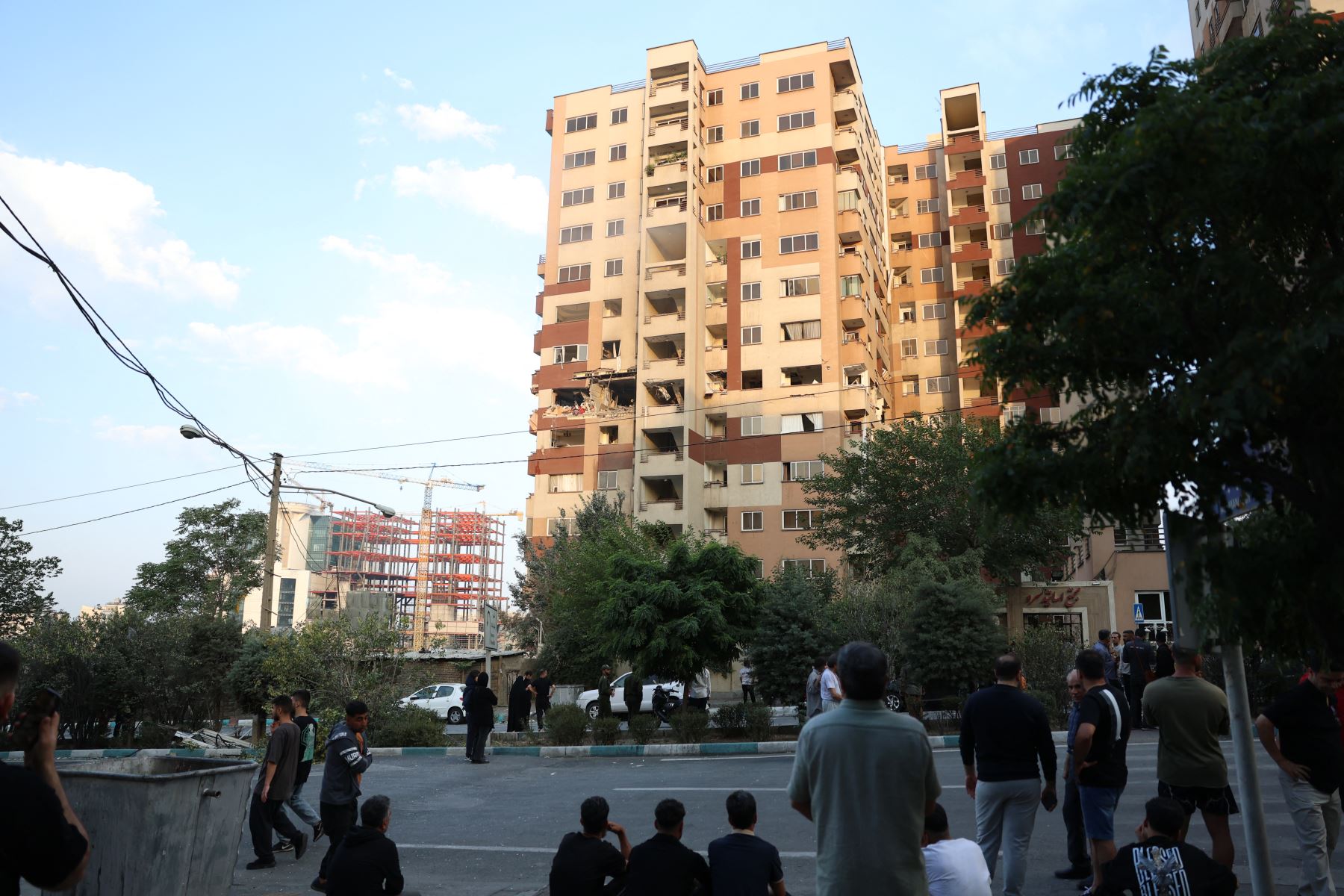 Los espectadores se reúnen frente a un edificio dañado en un ataque israelí contra la capital iraní, Teherán, el 13 de junio de 2025. Israel llevó a cabo ataques contra Irán la madrugada del 13 de junio, dirigidos contra sus instalaciones nucleares y militares. AFP