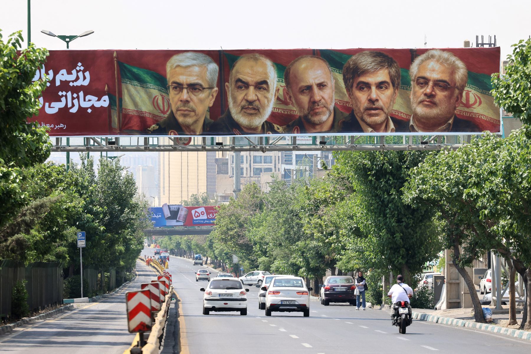 Un cartel con los retratos de generales militares y científicos nucleares iraníes, caídos en el ataque israelí la madrugada del 13 de junio, cuelga de un puente en Teherán.
Foto: AFP
