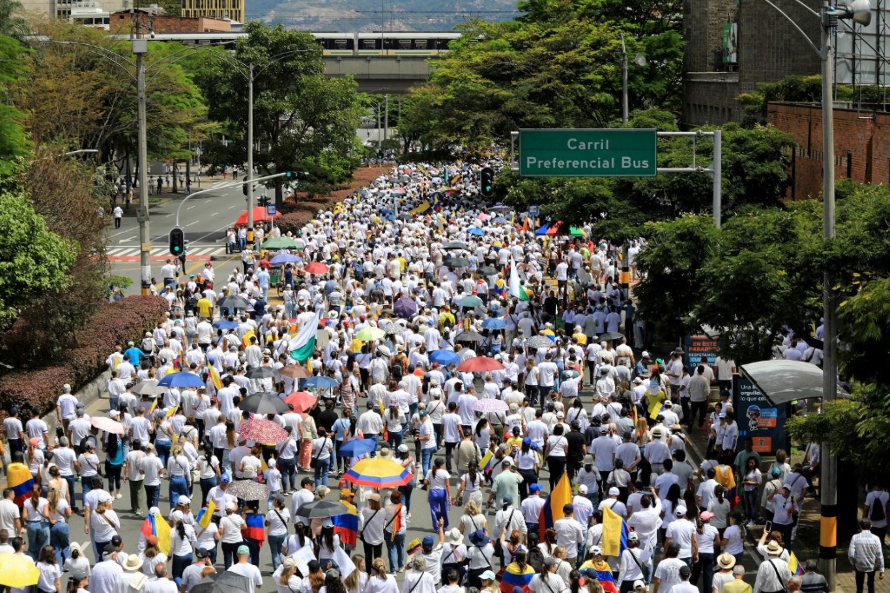 Personas con camisetas blancas y banderas colombianas participan en la llamada "Marcha Silenciosa" para expresar su apoyo a la salud del senador Miguel Uribe Turbay y pedir la paz en el país en Medellín, Colombia, el 15 de junio de 2025. Foto: AFP
