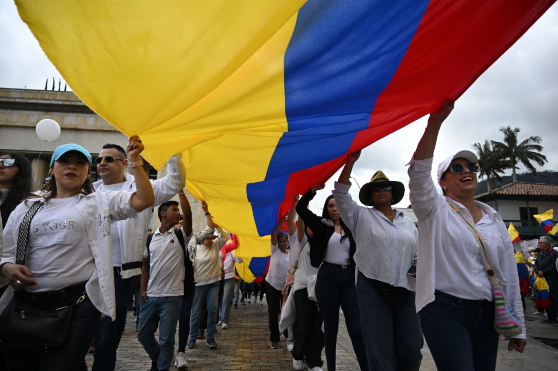 Decenas de personas sostienen una gran bandera colombiana durante la llamada "Marcha Silenciosa" para mostrar su apoyo a la salud del senador Miguel Uribe Turbay y pedir la paz para Colombia en Bogotá el 15 de junio de 2025. Foto: AFP