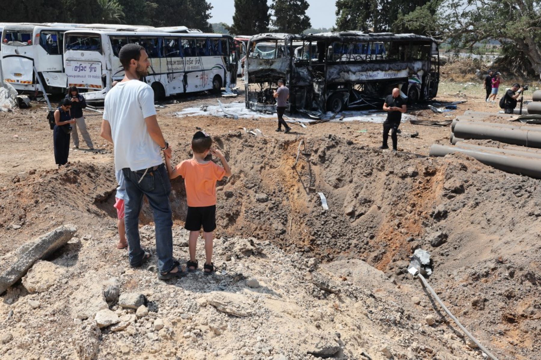 Personas observan se encuentran frente a un enorme cráter en el lugar del impacto de un misil iraní en una estación de autobuses en Herzliya, cerca de Tel Aviv. Foto: AFP