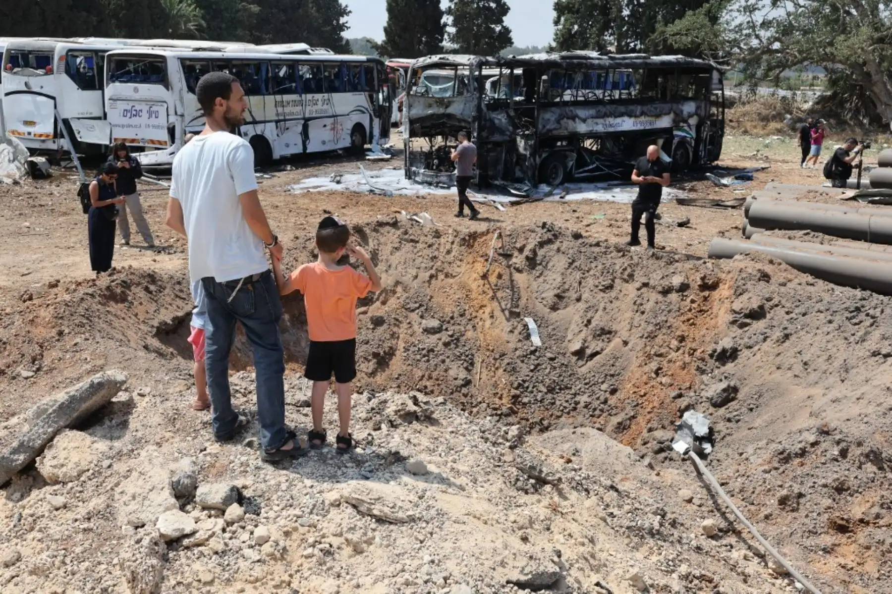 Personas observan se encuentran frente a un enorme cráter en el lugar del impacto de un misil iraní en una estación de autobuses en Herzliya, cerca de Tel Aviv. Foto: AFP