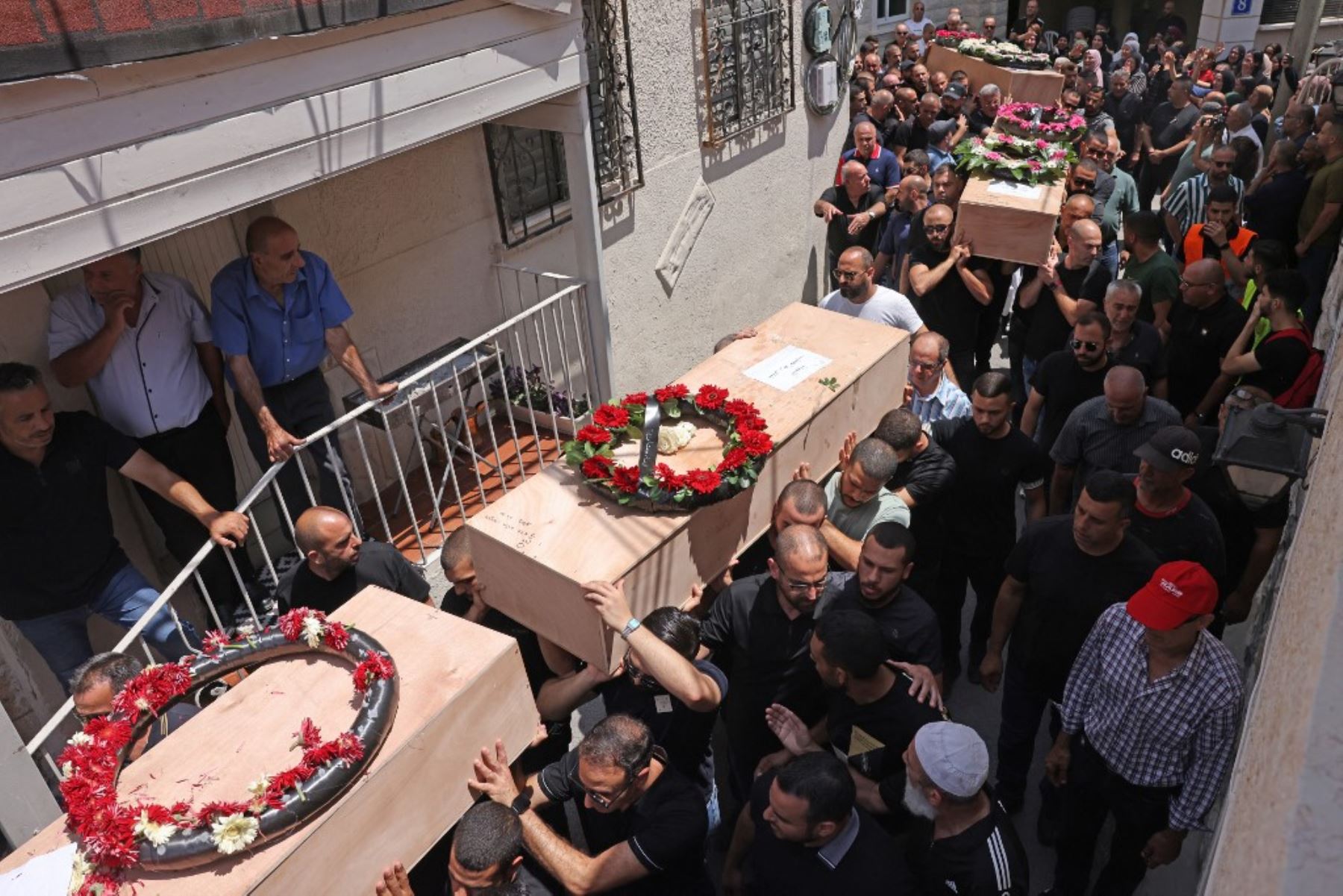 Familiares y amigos lloran los ataúdes de las víctimas de un ataque con misiles iraníes que destruyó un edificio de tres plantas en la ciudad de Tamra, en el norte de Israel, el fin de semana, y causó la muerte de cuatro mujeres, durante un funeral celebrado en Tamra. Foto: AFP