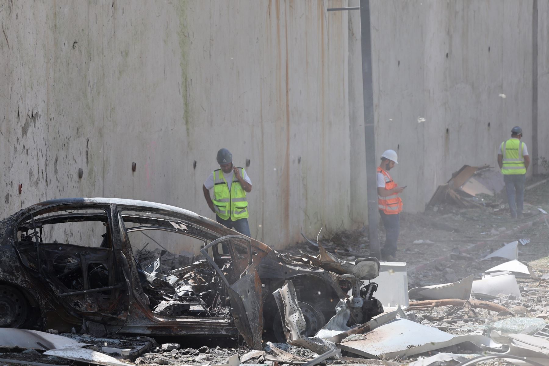 Personal de emergencias israelí se encuentra cerca de un vehículo dañado entre los escombros en el lugar del ataque con misiles iraníes en una zona residencial de Ramat Gan, en el centro de Israel. Foto: AFP
