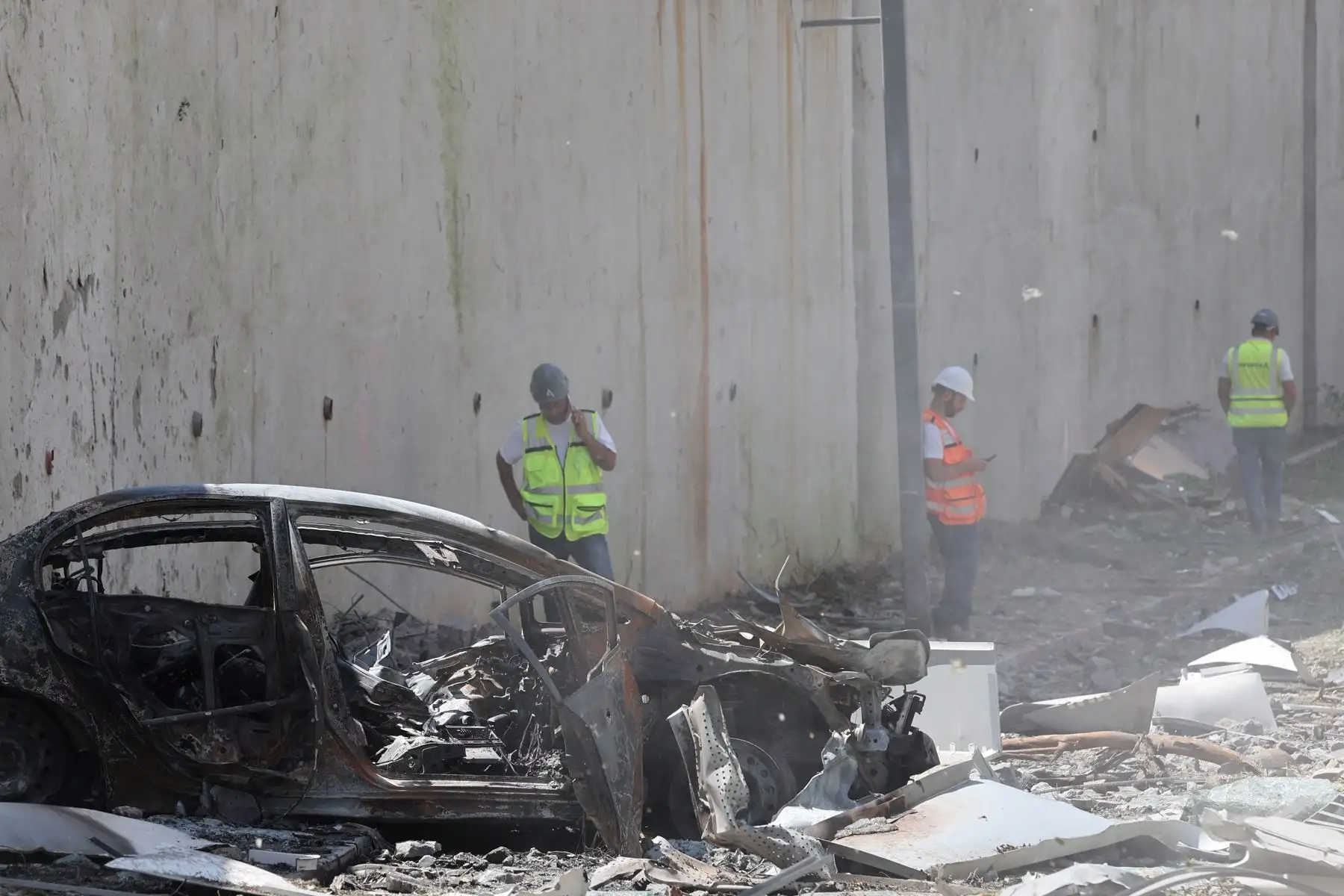 Personal de emergencias israelí se encuentra cerca de un vehículo dañado entre los escombros en el lugar del ataque con misiles iraníes en una zona residencial de Ramat Gan, en el centro de Israel. Foto: AFP
